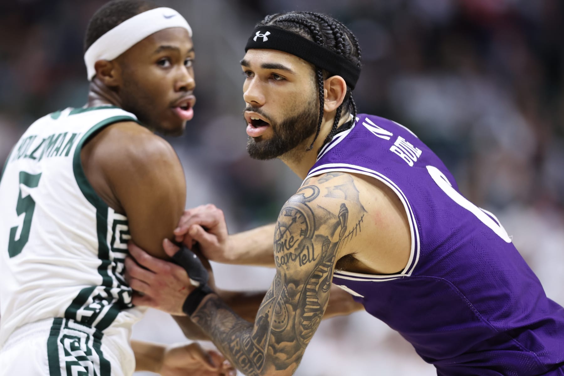 EAST LANSING, MICHIGAN - MARCH 6: Boo Buie #0 of the Northwestern Wildcats looks to break free from Tre Holloman #5 of the Michigan State Spartans during the first half of the game at Breslin Center on March 6, 2024 in East Lansing, Michigan. (Photo by Rey Del Rio/Getty Images)