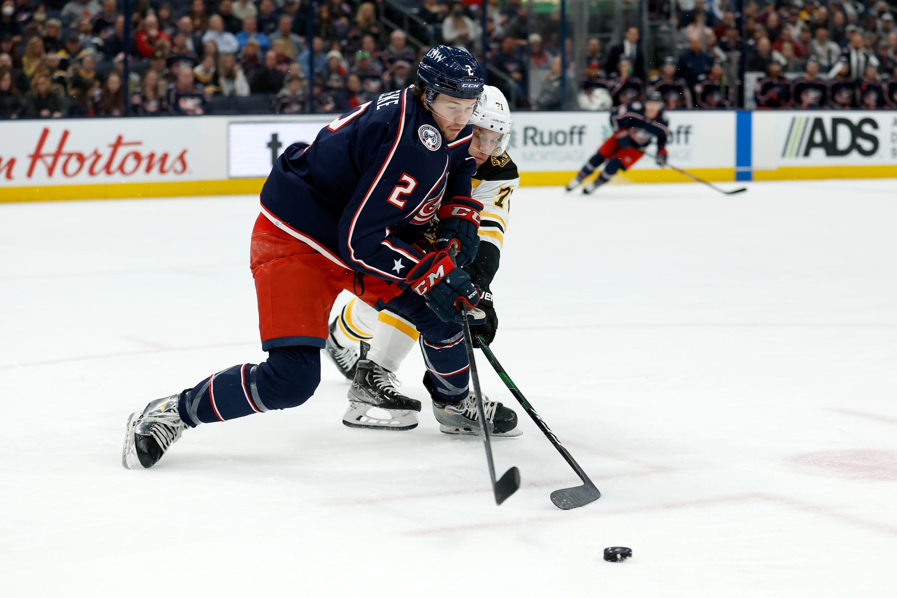 COLUMBUS, OH - APRIL 04: Andrew Peeke #2 of the Columbus Blue Jackets and Taylor Hall #71 of the Boston Bruins battle for control of the puck during the first period of the game at Nationwide Arena on April 4, 2022 in Columbus, Ohio. (Photo by Kirk Irwin/Getty Images)