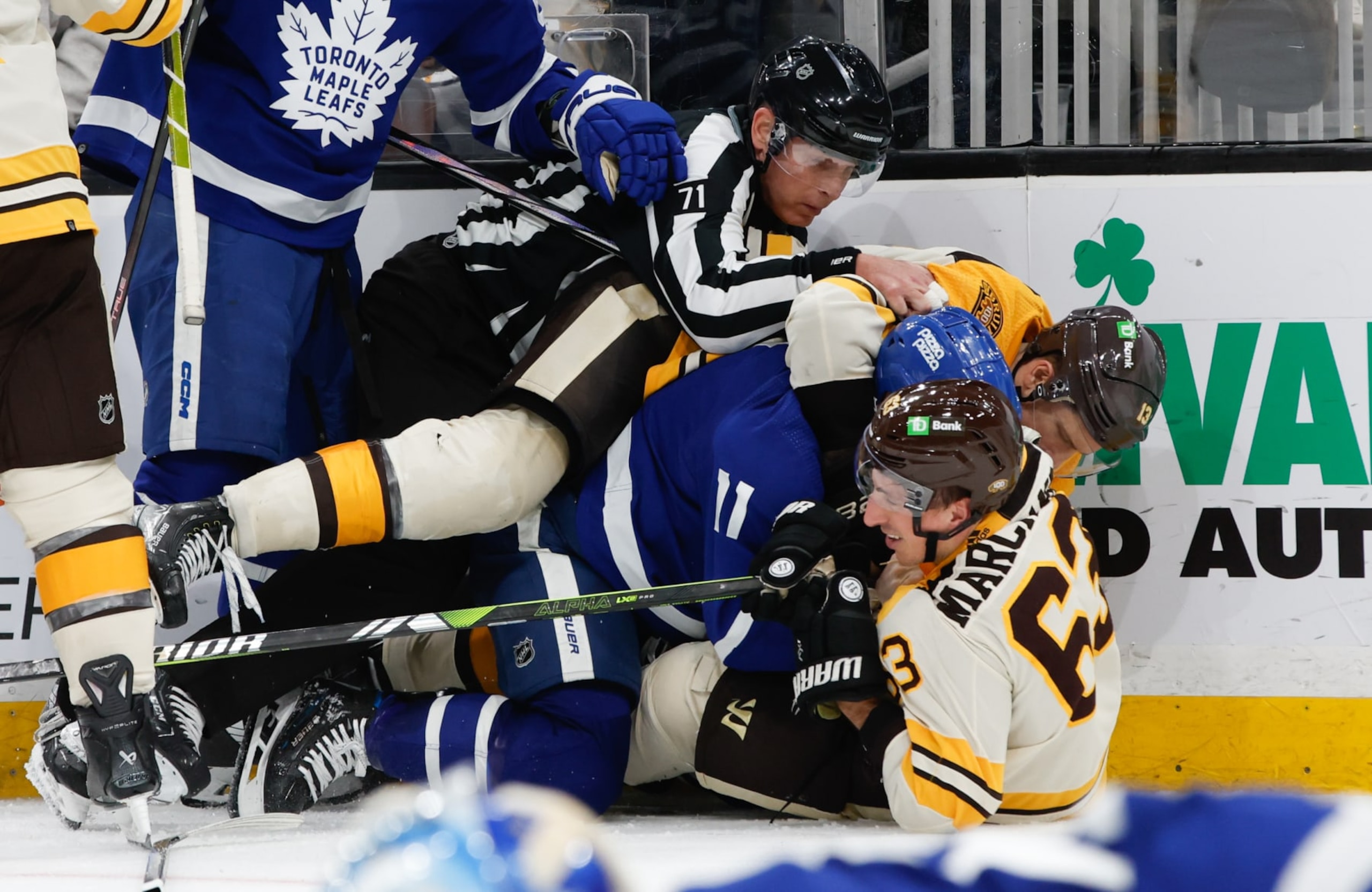 BOSTON, MASSACHUSETTS - MARCH 7: Brad Marchand #63 of the Boston Bruins is tangled-up with Max Domi #11 of the Toronto Maple Leafs as linesman Brad Kovachik #71 tries to break them up during the third period at the TD Garden on March 7, 2024 in Boston, Massachusetts. The Bruins won 4-1. (Photo by Richard T Gagnon/Getty Images)