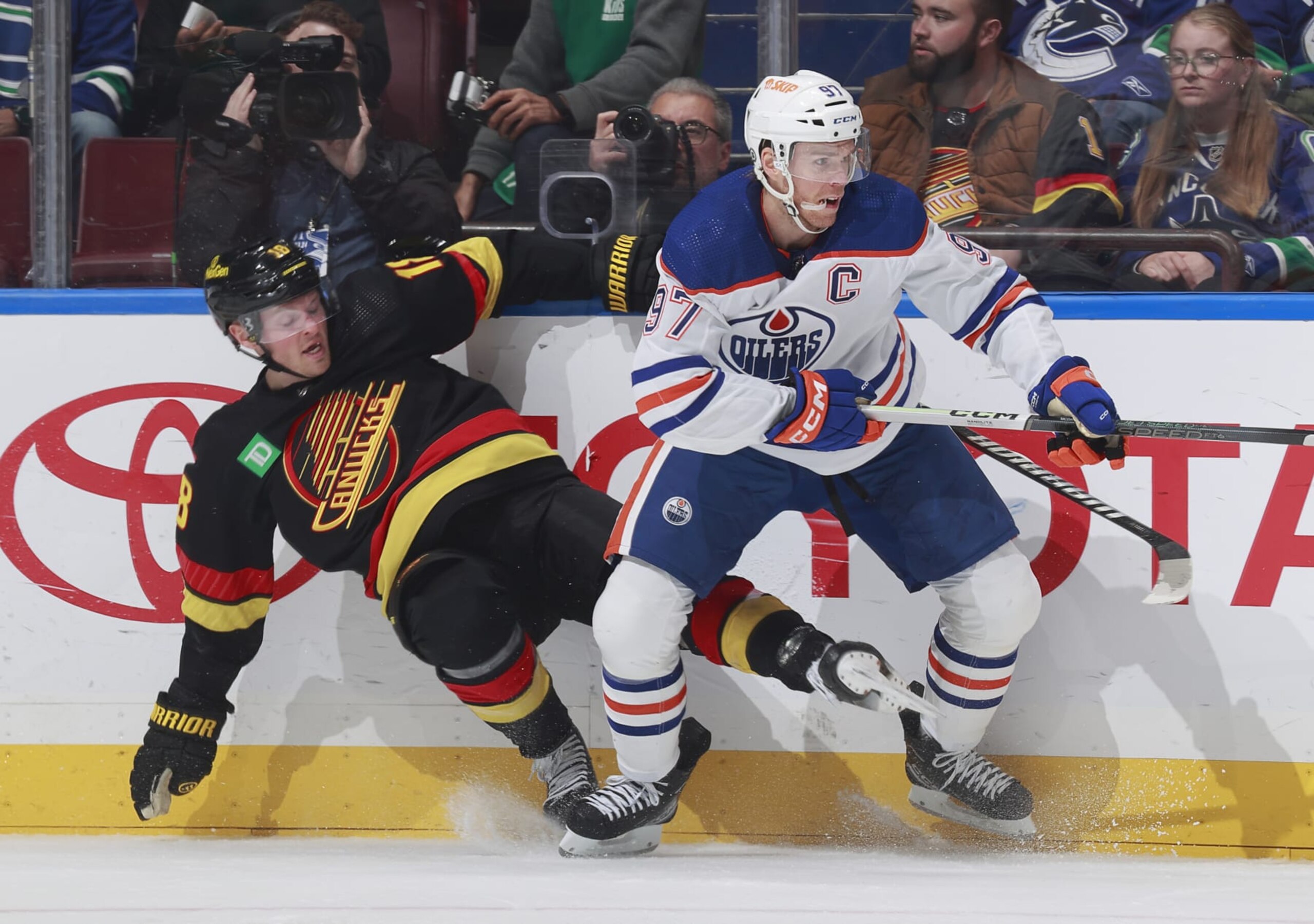 VANCOUVER, CANADA - NOVEMBER 6: Connor McDavid #97 of the Edmonton Oilers checks Sam Lafferty #18 of the Vancouver Canucks during their NHL game at Rogers Arena on November 6, 2023 in Vancouver, British Columbia, Canada.  (Photo by Jeff Vinnick/NHLI via Getty Images)