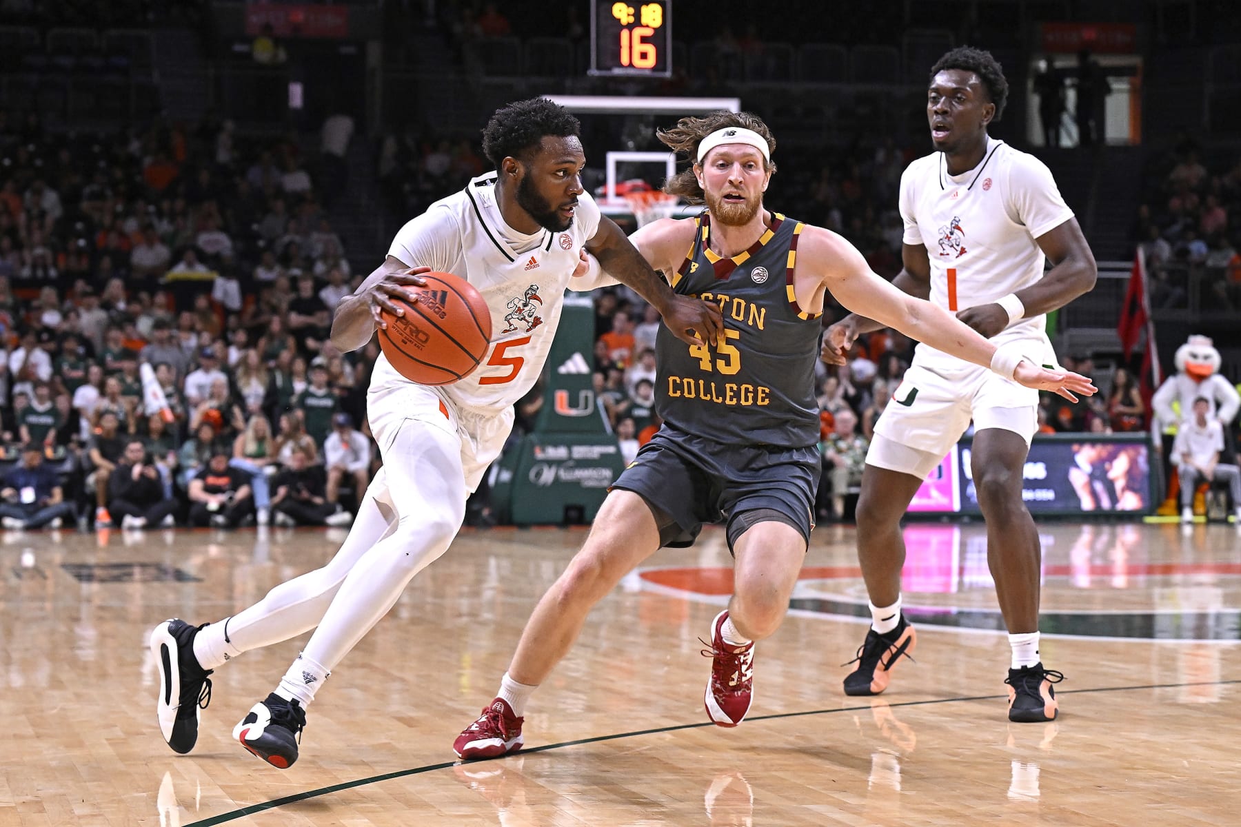 CORAL GABLES, FL - MARCH 06: Miami guard Wooga Poplar (5) drives to the basket while defended by Boston College guard Mason Madsen (45) in the first half (also pictured, Miami center Michael Nwoko (1)) as the Miami Hurricanes faced the Boston College Eagles on March 6, 2024, at the Watsco Center in Coral Gables, Florida. (Photo by Samuel Lewis/Icon Sportswire via Getty Images)