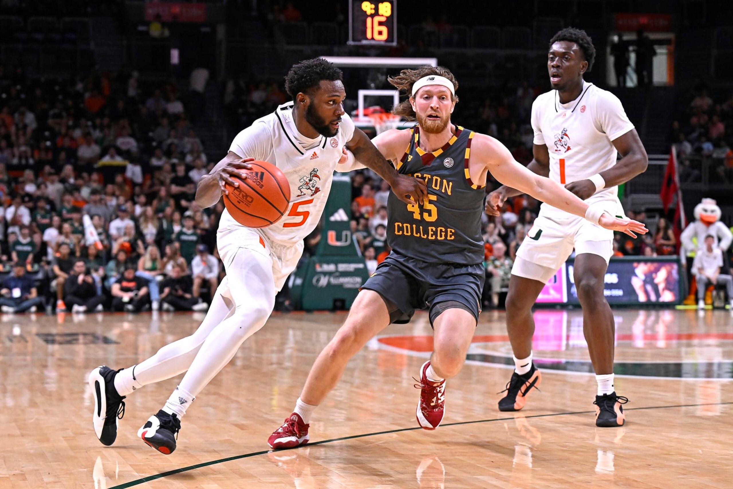 CORAL GABLES, FL - MARCH 06: Miami guard Wooga Poplar (5) drives to the basket while defended by Boston College guard Mason Madsen (45) in the first half (also pictured, Miami center Michael Nwoko (1)) as the Miami Hurricanes faced the Boston College Eagles on March 6, 2024, at the Watsco Center in Coral Gables, Florida. (Photo by Samuel Lewis/Icon Sportswire via Getty Images)