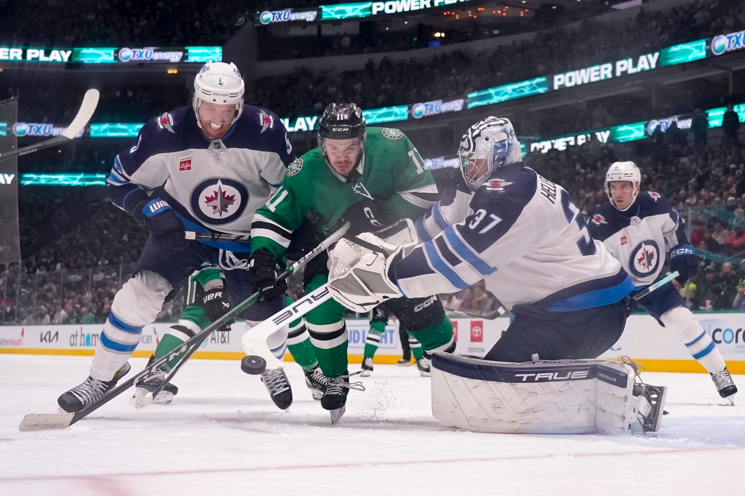 DALLAS, TEXAS - FEBRUARY 29: Logan Stankoven #11 of the Dallas Stars compete for the puck against Brenden Dillon #5 and Connor Hellebuyck #37 of the Winnipeg Jets during the third period at American Airlines Center on February 29, 2024 in Dallas, Texas. (Photo by Sam Hodde/Getty Images)