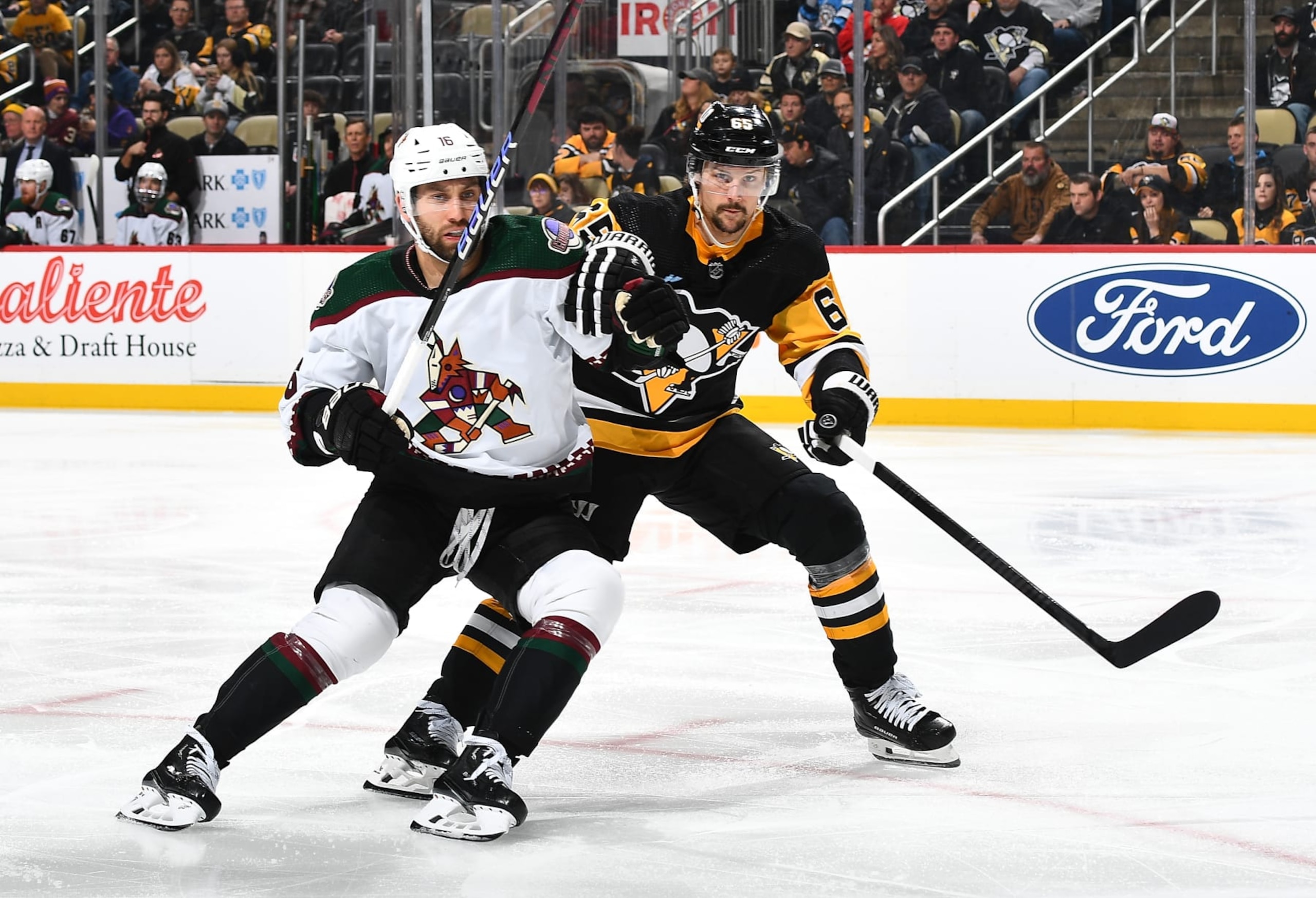 PITTSBURGH, PA - DECEMBER 12:  Jason Zucker #16 of the Arizona Coyotes and Erik Karlsson #65 of the Pittsburgh Penguins battle for position at PPG PAINTS Arena on December 12, 2023 in Pittsburgh, Pennsylvania. (Photo by Joe Sargent/NHLI via Getty Images)