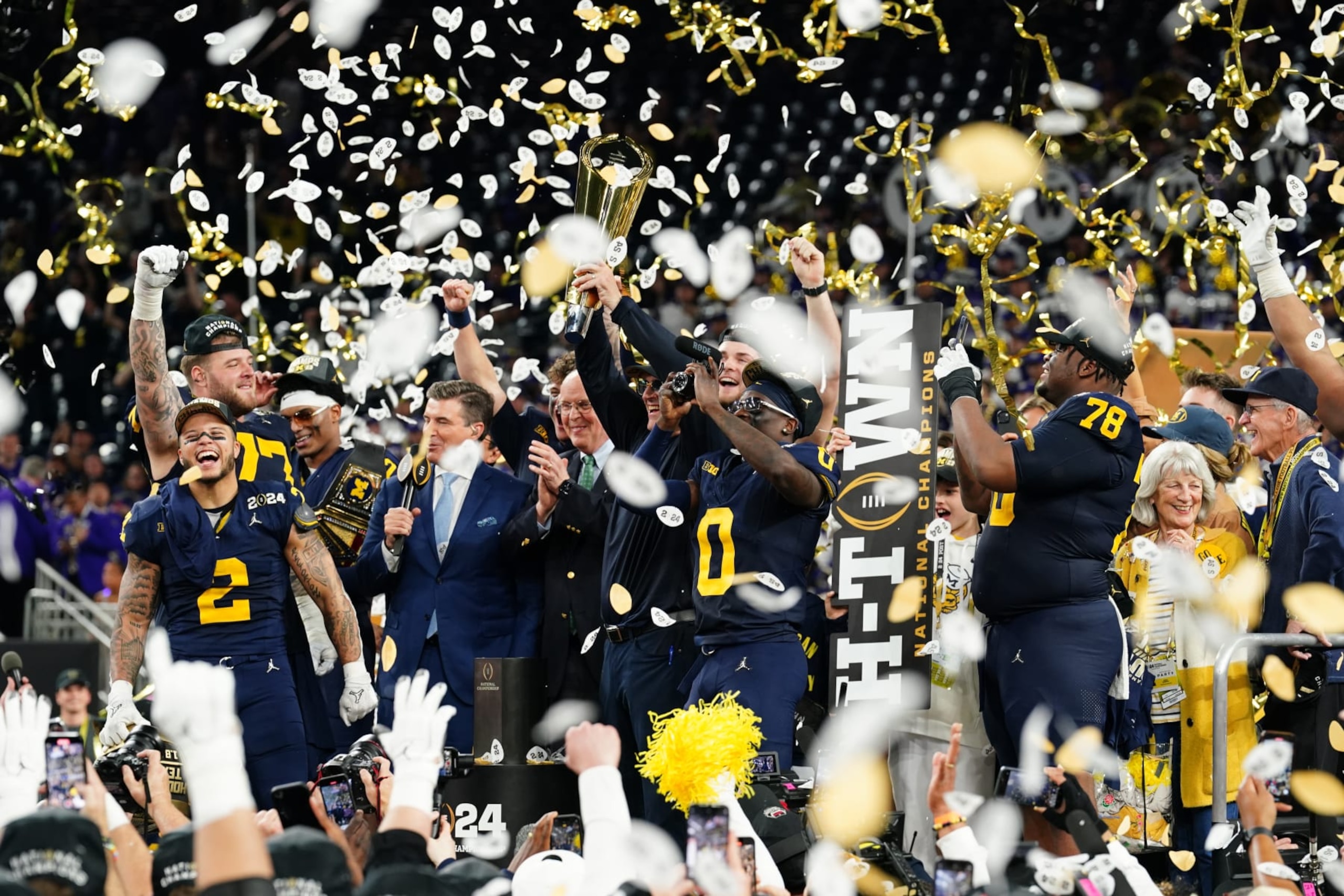 HOUSTON, TX - JANUARY 08: (L-R) RB Blake Corum (2), OL Trevor Keegan (77), DB Will Johnson (2), Head Coach Jim Harbaugh, DB Mike Sainristil (0) and DL Kenneth Grant (78) celebrates with the championship trophy after the Wolverines defeat the Washington Huskies 34-13 in the CFP National Championship game on January 8, 2024, at NRG Stadium in Houston, TX. (Photo by Daniel Dunn/Icon Sportswire via Getty Images) HOUSTON, TX - JANUARY 08: (L-R) RB Blake Corum (2), OL Trevor Keegan (77), DB Will Johnson (2), Head Coach Jim Harbaugh, DB Mike Sainristil (0) and DL Kenneth Grant (78) celebrates with the championship trophy after the Wolverines defeat the Washington Huskies 34-13 in the CFP National Championship game on January 8, 2024, at NRG Stadium in Houston, TX. (Photo by Daniel Dunn/Icon Sportswire via Getty Images)