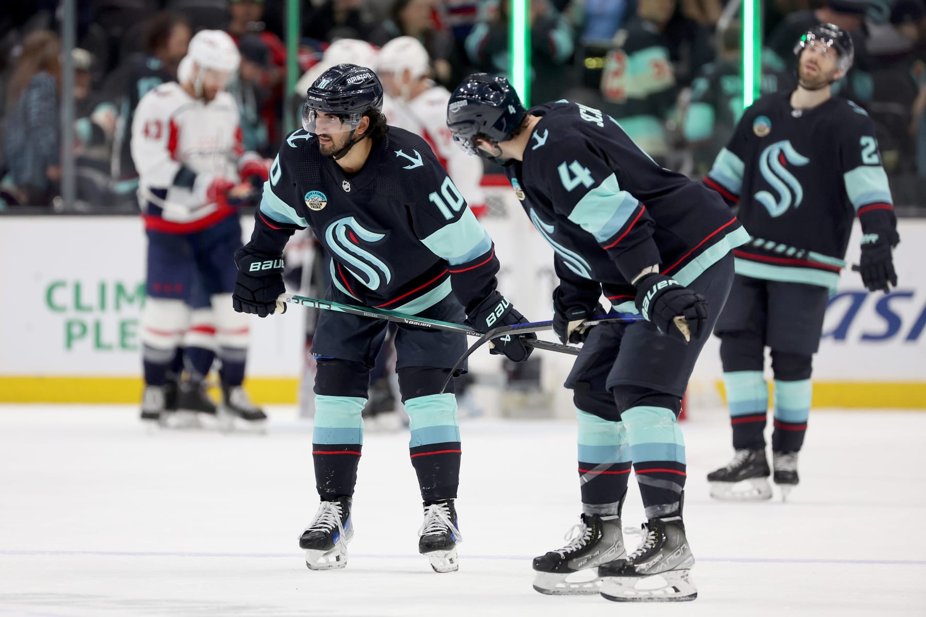 SEATTLE, WASHINGTON - MARCH 14: Matty Beniers #10, Justin Schultz #4 and Oliver Bjorkstrand #22 of the Seattle Kraken react after losing 2-1 to the Washington Capitals at Climate Pledge Arena on March 14, 2024 in Seattle, Washington. (Photo by Steph Chambers/Getty Images)