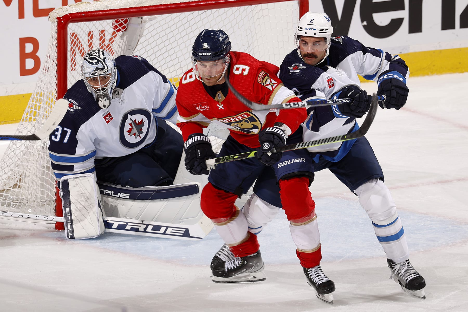 SUNRISE, FLORIDA - NOVEMBER 24: Goaltender Connor Hellebuyck #37 of the Winnipeg Jets defends the net with the help of teammate Dylan DeMelo #2 against Sam Bennett #9 of the Florida Panthers at the Amerant Bank Arena on November 24, 2023 in Sunrise, Florida. (Photo by Eliot J. Schechter/NHLI via Getty Images)