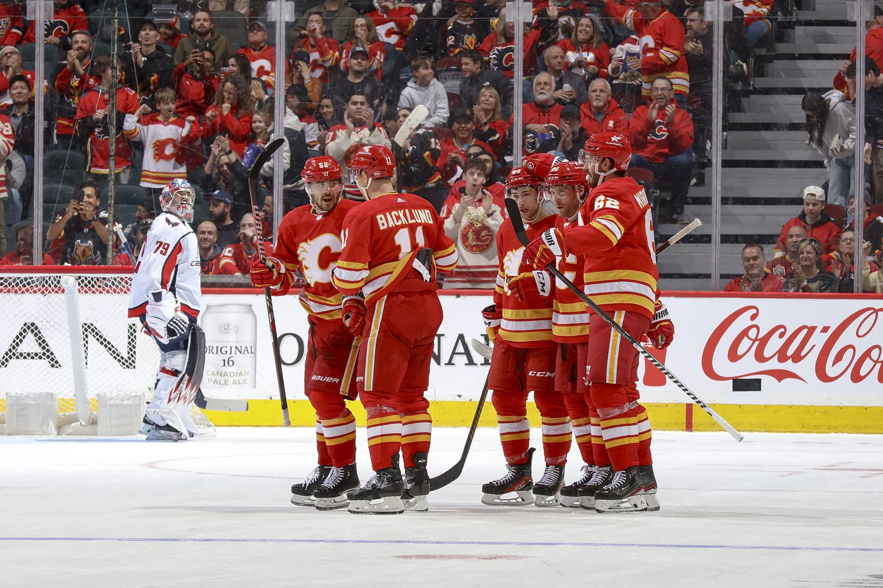 iCALGARY, AB - MARCH 18: MacKenzie Weegar #52 of the Calgary Flames celebrates with teammates after a goal against the Washington Capitals at Scotiabank Saddledome on March 18, 2024 in Calgary, Alberta, Canada. (Photo by Gerry Thomas/NHLI via Getty Images)