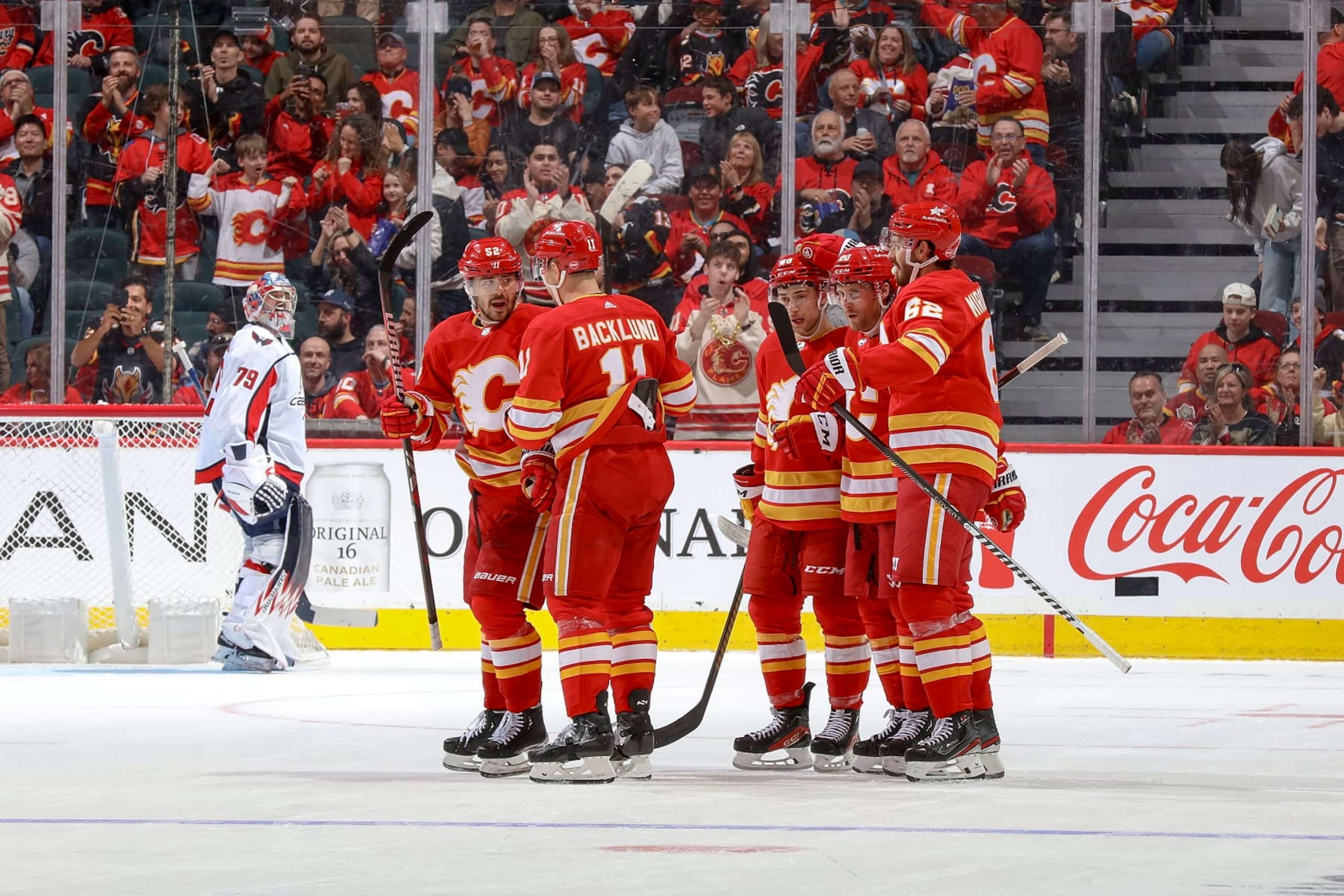 iCALGARY, AB - MARCH 18: MacKenzie Weegar #52 of the Calgary Flames celebrates with teammates after a goal against the Washington Capitals at Scotiabank Saddledome on March 18, 2024 in Calgary, Alberta, Canada. (Photo by Gerry Thomas/NHLI via Getty Images)