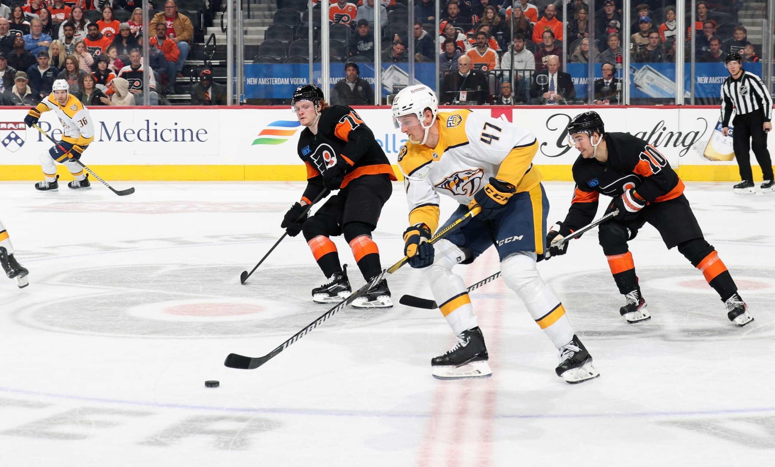 PHILADELPHIA, PENNSYLVANIA - DECEMBER 21:  Michael Carrier #47 of the Nashville Predators skates the puck against Bobby Brink #10 and Owen Tippett #74 of the Philadelphia Flyers at the Wells Fargo Center on December 21, 2023 in Philadelphia, Pennsylvania.  (Photo by Len Redkoles/NHLI via Getty Images)