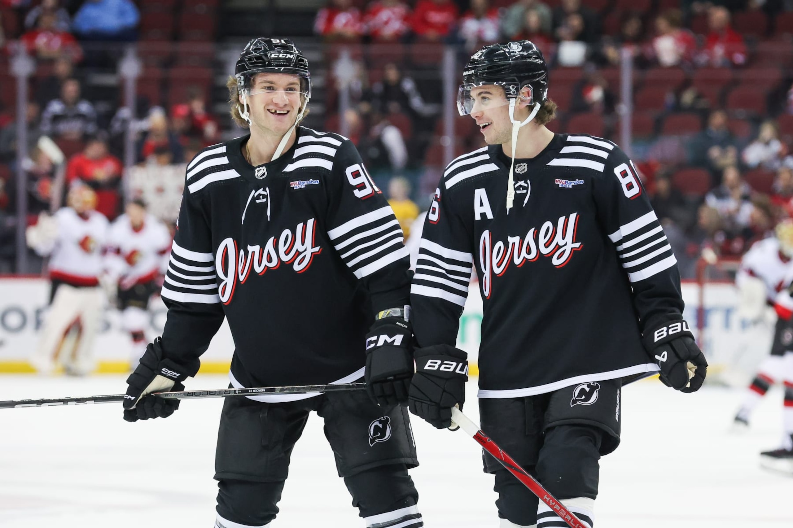NEWARK, NJ - MARCH 23: New Jersey Devils center Dawson Mercer (91) and New Jersey Devils center Jack Hughes (86) share a laugh in warmups before a game between the Ottawa Senators and New Jersey Devils on March 23, 2024 at Prudential Center in the Newark, New Jersey. (Photo by Andrew Mordzynski/Icon Sportswire via Getty Images)