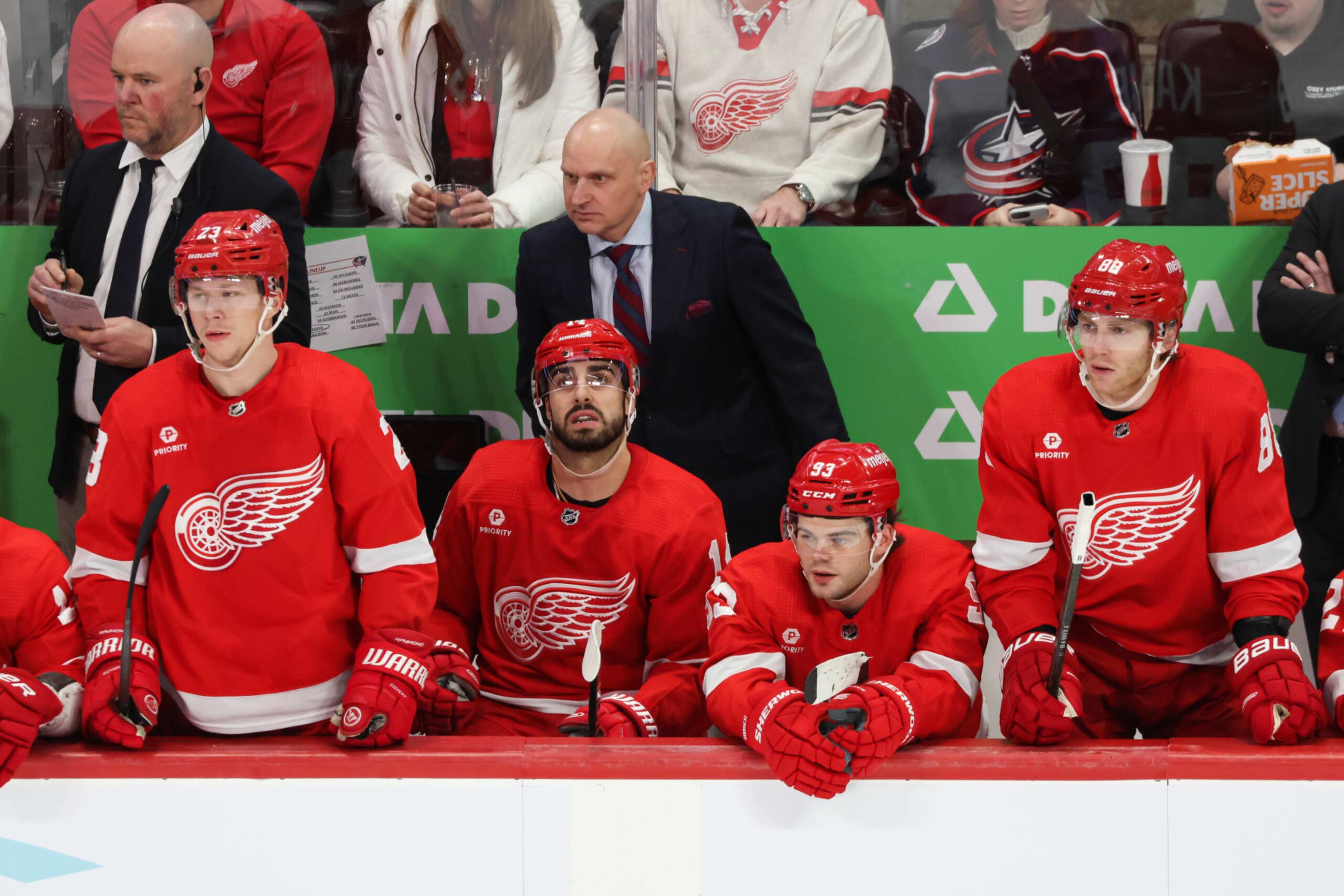 DETROIT, MI - MARCH 19:  From the left, Detroit Red Wings forwards Lucas Raymond (23), Robby Fabbri (14), Alex DeBrincat (93), and Patrick Kane (88) and Detroit Red Wings head coach Derek Lalonde, behind, watch the action on the ice during an NHL regular season hockey game between the Columbus Blue Jackets  and the Detroit Red Wings on March 19, 2024 at Little Caesars Arena in Detroit, Michigan. (Photo by Scott W. Grau/Icon Sportswire via Getty Images)
