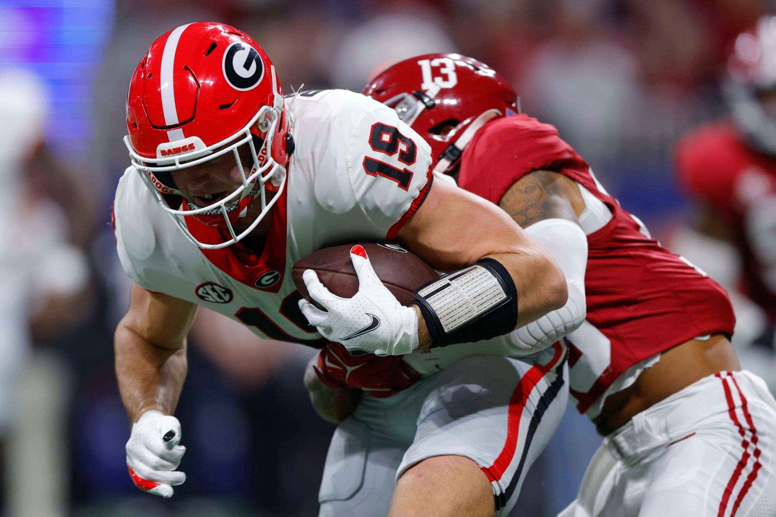 ATLANTA, GEORGIA - DECEMBER 2: Brock Bowers #19 of the Georgia Bulldogs is tackled by Malachi Moore #13 of the Alabama Crimson Tide during the first quarter in the SEC Championship at Mercedes-Benz Stadium on December 2, 2023 in Atlanta, Georgia. (Photo by Todd Kirkland/Getty Images)