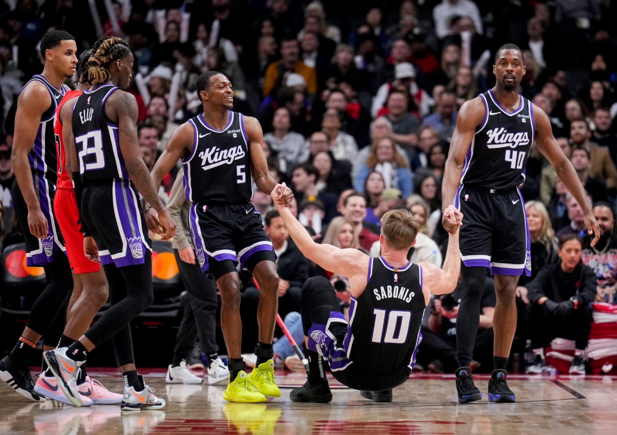 TORONTO, ON - MARCH 20: Domantas Sabonis #10 of the Sacramento Kings is helped up by teammates De'Aaron Fox #5 and Harrison Barnes #40 against the Toronto Raptors in the second half at the Scotiabank Arena on March 20, 2024 in Toronto, Ontario, Canada. NOTE TO USER: User expressly acknowledges and agrees that, by downloading and/or using this Photograph, user is consenting to the terms and conditions of the Getty Images License Agreement. (Photo by Mark Blinch/Getty Images)