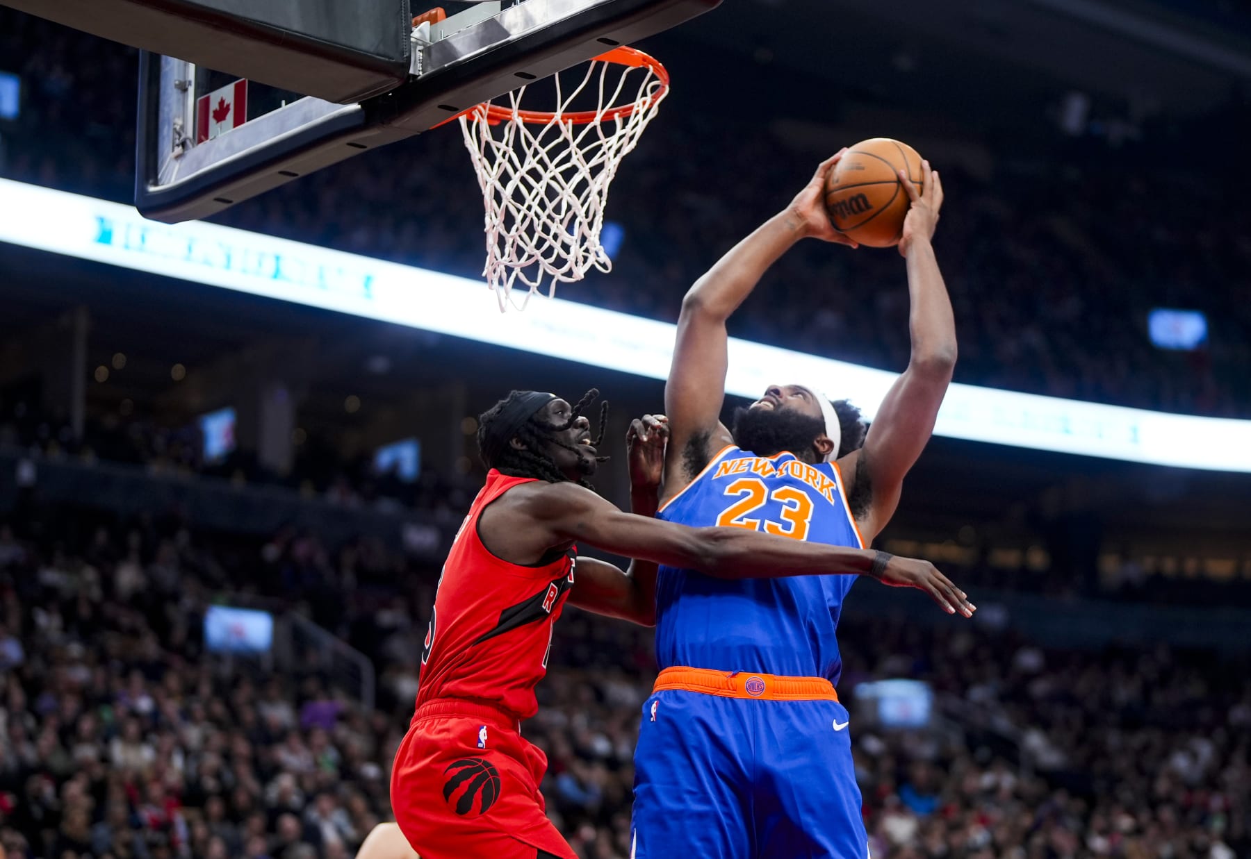 TORONTO, ON - MARCH 27: Mitchell Robinson #23 of the New York Knicks goes to the basket against Mouhamadou Gueye #16 of the Toronto Raptors during the first half of their basketball game at the Scotiabank Arena on March 27, 2024 in Toronto, Ontario, Canada. NOTE TO USER: User expressly acknowledges and agrees that, by downloading and/or using this Photograph, user is consenting to the terms and conditions of the Getty Images License Agreement. (Photo by Mark Blinch/Getty Images)