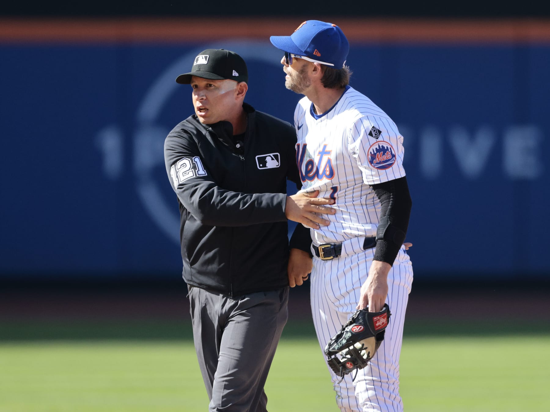 NEW YORK, NEW YORK - MARCH 29: Jeff McNeil #1 of the New York Mets is held back by umpire Jonathan Parra #121 after a play involving Rhys Hoskins #12 of the Milwaukee Brewers during the top of the eighth inning in the home opener at Citi Field on March 29, 2024 in New York City. (Photo by Christopher Pasatieri/Getty Images)
