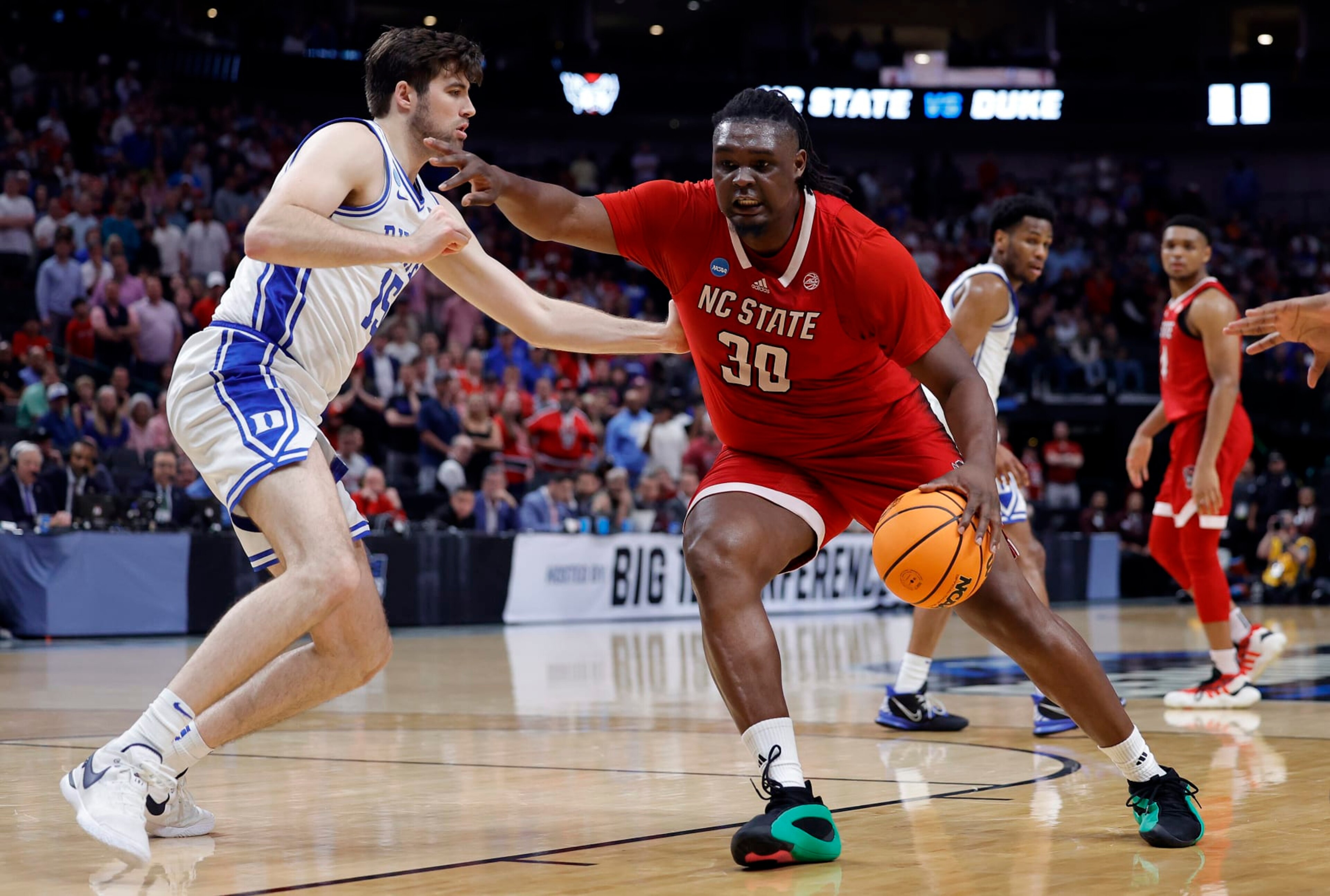 DALLAS, TEXAS - MARCH 31:  DJ Burns Jr. #30 of the North Carolina State Wolfpack controls the ball as Ryan Young #15 of the Duke Blue Devils defends in the Elite 8 round of the NCAA Men's Basketball Tournament at American Airlines Center on March 31, 2024 in Dallas, Texas. (Photo by Carmen Mandato/Getty Images)