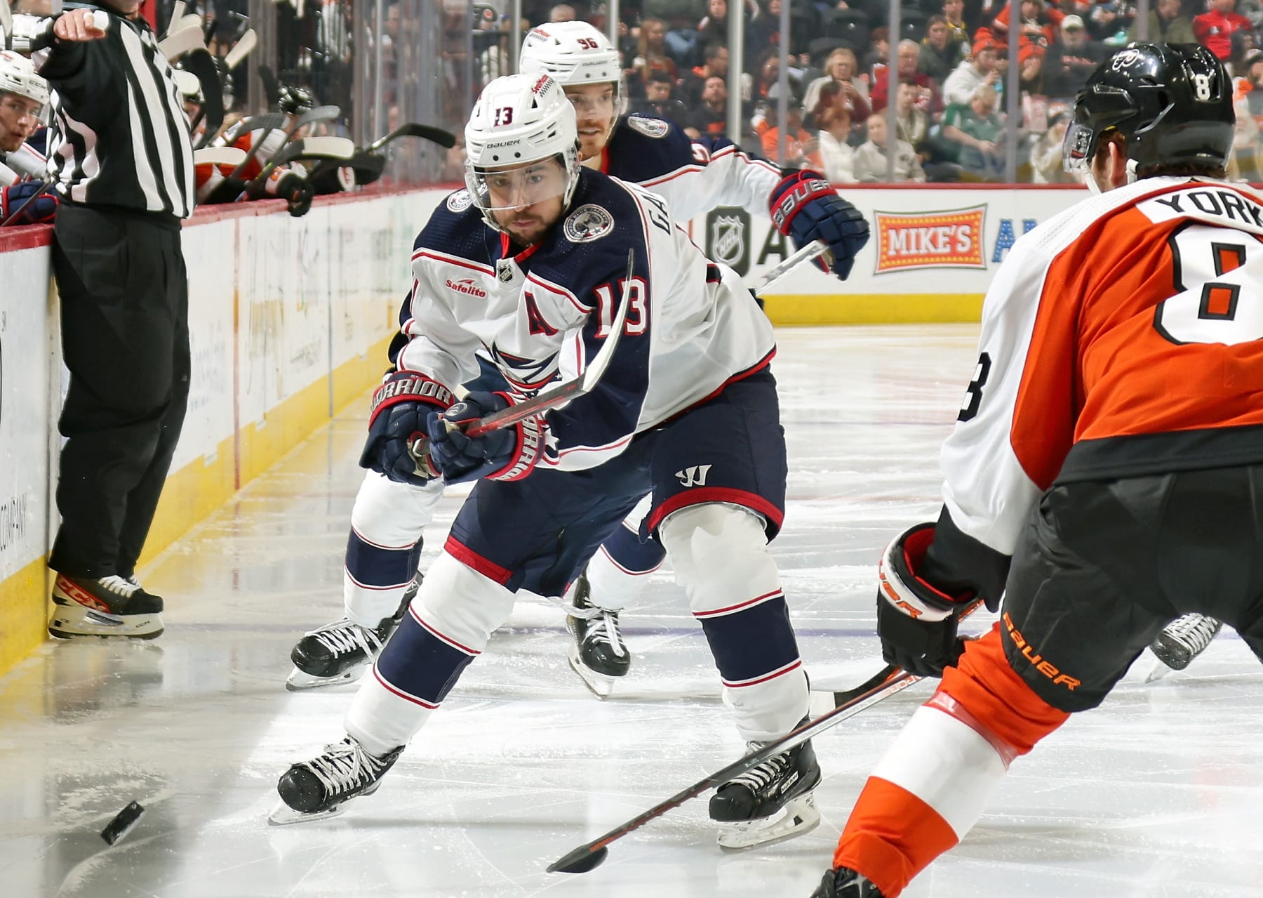 PHILADELPHIA, PENNSYLVANIA - JANUARY 04:  Johnny Gaudreau #13 of the Columbus Blue Jackets dumps the puck along the boards against Cam York #8 of the Philadelphia Flyers at the Wells Fargo Center on January 4, 2024 in Philadelphia, Pennsylvania.  (Photo by Len Redkoles/NHLI via Getty Images)