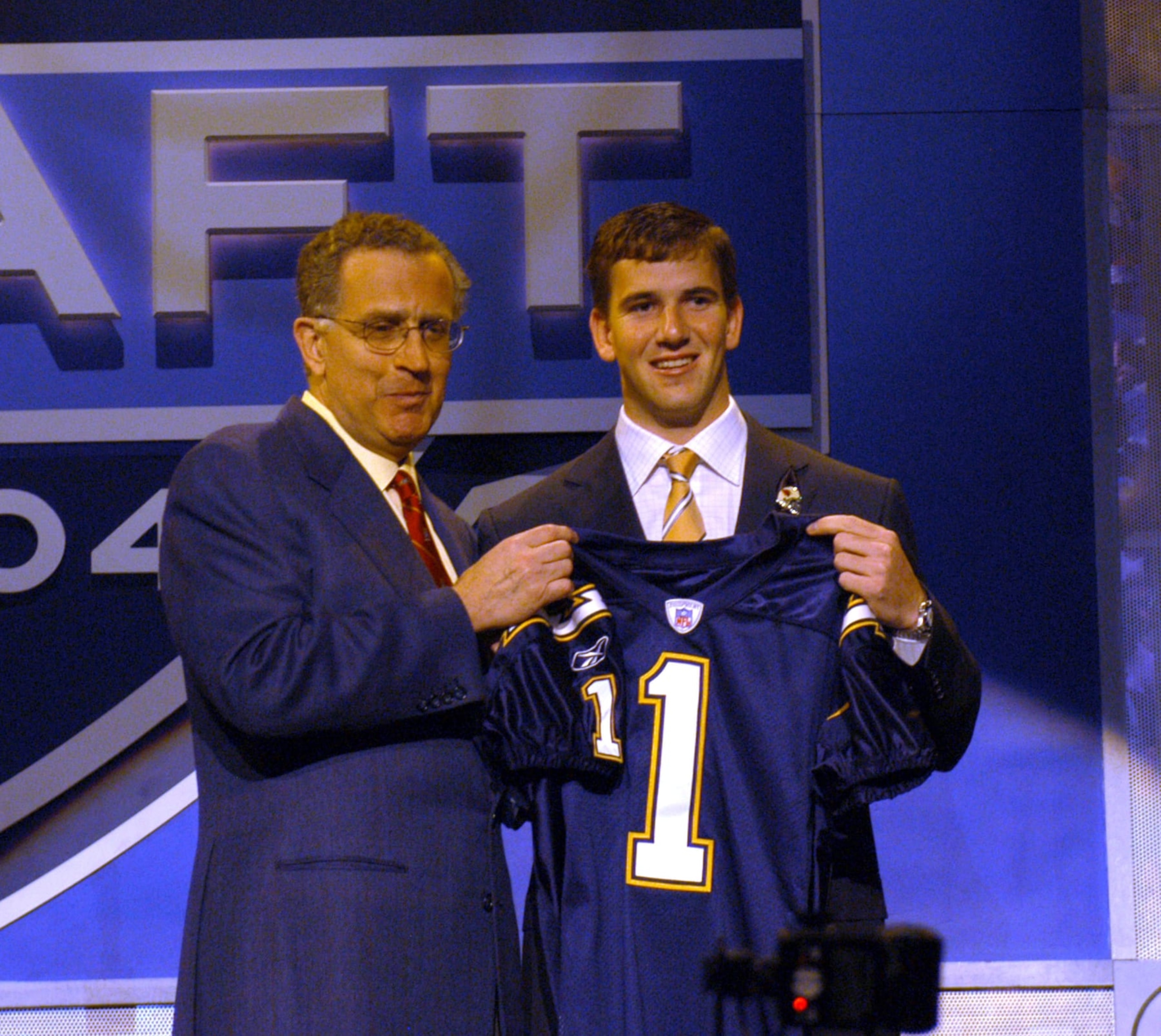 2004 NFL Draft first overall pick Eli Manning (right) with NFL Commisioner Paul Tagliabue, at Madison Square Garden in New York, April 24. Manning, shown with San Diego Chargers jersey, was traded to the New York Giants later in the day. (Photo by Allan Grdovic/Getty Images) 2004 NFL Draft first overall pick Eli Manning (right) with NFL Commisioner Paul Tagliabue, at Madison Square Garden in New York, April 24. Manning, shown with San Diego Chargers jersey, was traded to the New York Giants later in the day. (Photo by Allan Grdovic/Getty Images)
