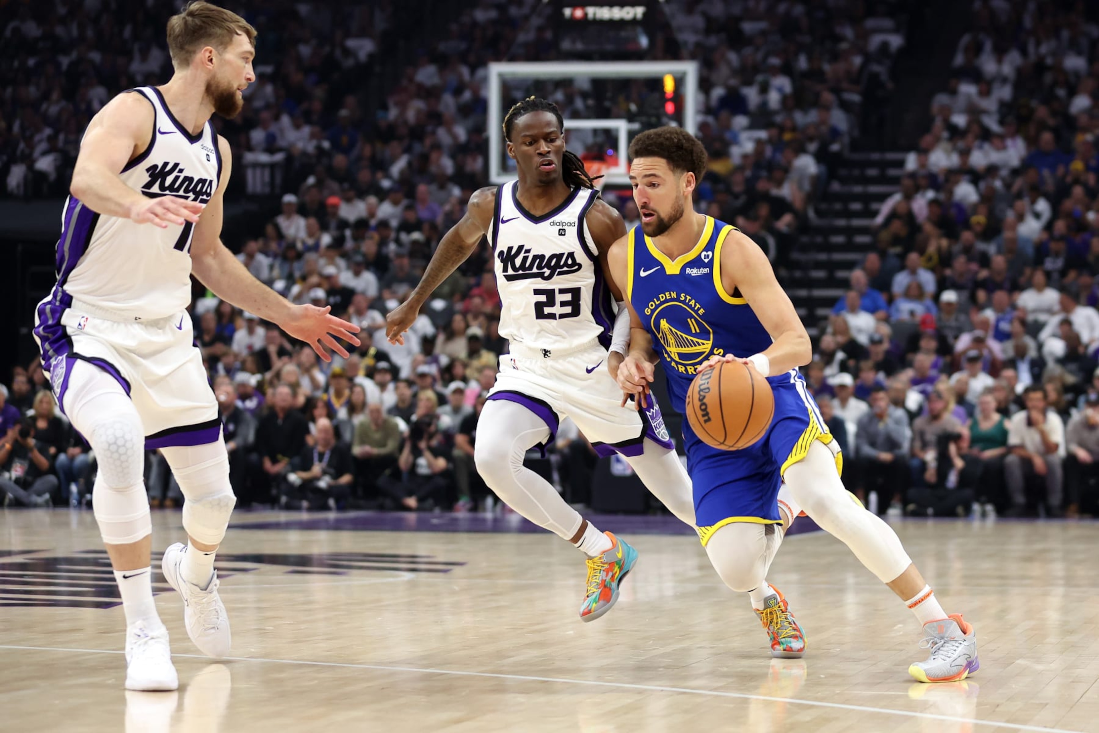 SACRAMENTO, CALIFORNIA - APRIL 16: Klay Thompson #11 of the Golden State Warriors is guarded by Keon Ellis #23 and Domantas Sabonis #10 of the Sacramento Kings in the first quarter during the Play-In Tournament at Golden 1 Center on April 16, 2024 in Sacramento, California.  NOTE TO USER: User expressly acknowledges and agrees that, by downloading and or using this photograph, User is consenting to the terms and conditions of the Getty Images License Agreement.  (Photo by Ezra Shaw/Getty Images)