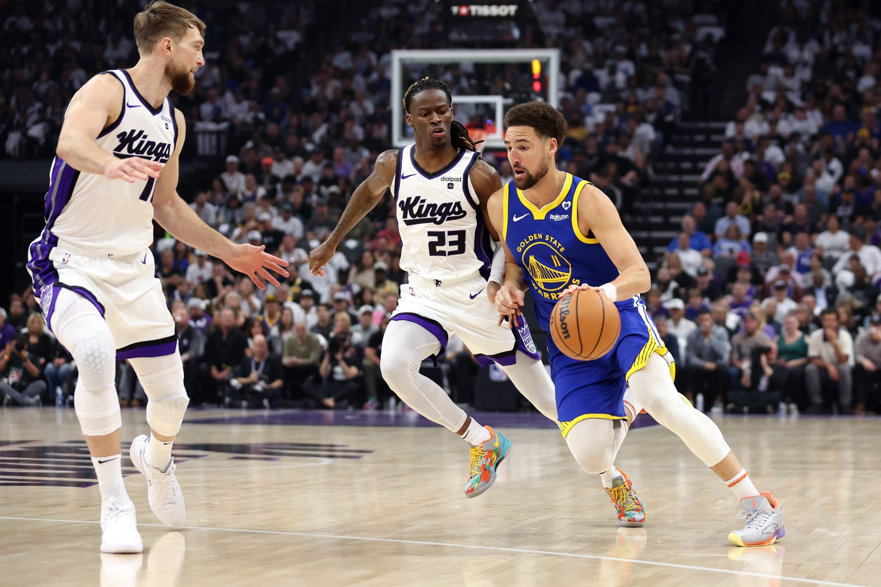 SACRAMENTO, CALIFORNIA - APRIL 16: Klay Thompson #11 of the Golden State Warriors is guarded by Keon Ellis #23 and Domantas Sabonis #10 of the Sacramento Kings in the first quarter during the Play-In Tournament at Golden 1 Center on April 16, 2024 in Sacramento, California.  NOTE TO USER: User expressly acknowledges and agrees that, by downloading and or using this photograph, User is consenting to the terms and conditions of the Getty Images License Agreement.  (Photo by Ezra Shaw/Getty Images)