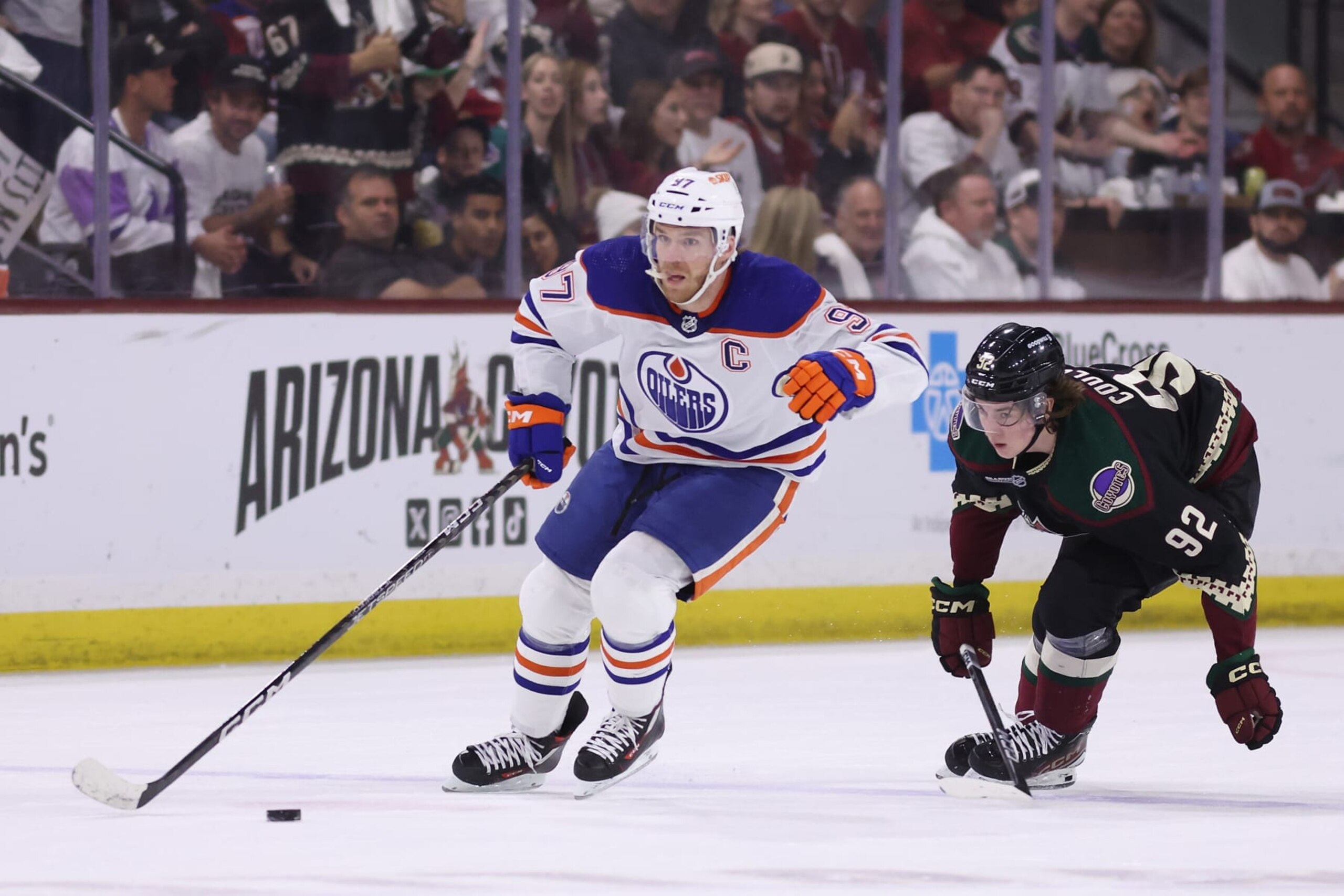 TEMPE, ARIZONA - APRIL 17: Connor McDavid #97 of the Edmonton Oilers skates with the puck ahead of Logan Cooley #92 of the Arizona Coyotes during the first period of the NHL game at Mullett Arena on April 17, 2024 in Tempe, Arizona. (Photo by Christian Petersen/Getty Images)