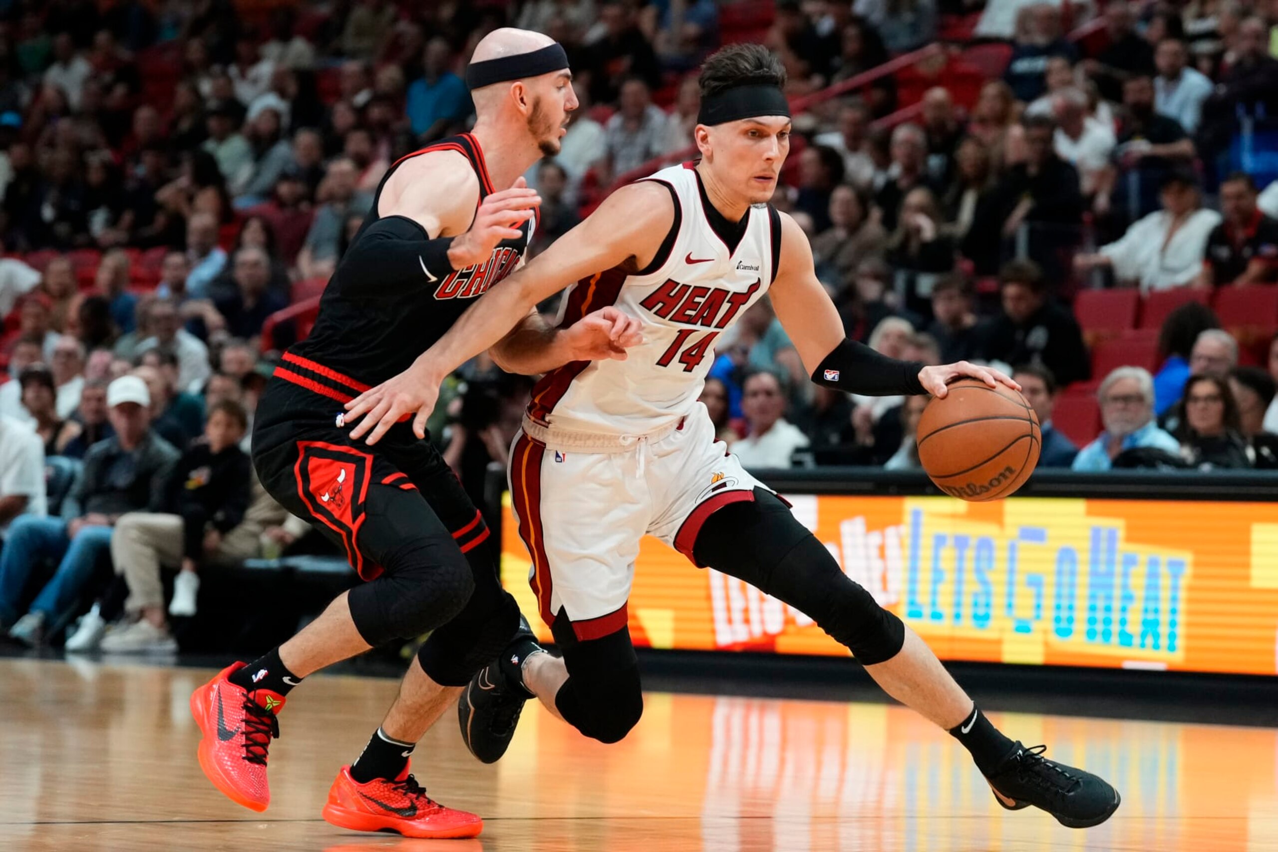 MIAMI, FLORIDA - APRIL 19: Tyler Herro #14 of the Miami Heat dribbles the ball against Alex Caruso #6 of the Chicago Bulls in the first quarter during the Play-In Tournament at Kaseya Center on April 19, 2024 in Miami, Florida. NOTE TO USER: User expressly acknowledges and agrees that, by downloading and or using this photograph, User is consenting to the terms and conditions of the Getty Images License Agreement. (Photo by Rich Storry/Getty Images)