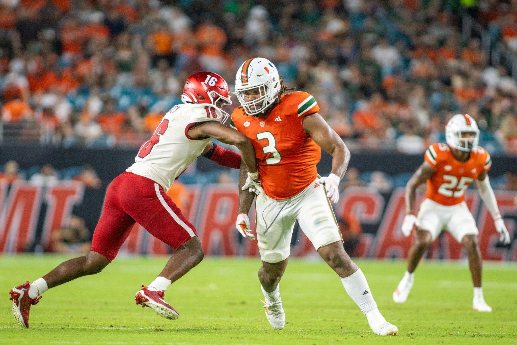 MIAMI GARDENS, FL - SEPTEMBER 1: Akheem Mesidor #3 of the Miami Hurricanes runs by Eli Blakey #16 of the Miami Ohio Redhawks during the third quarter during a game between Miami Ohio Redhawks and Miami Hurricanes at Hard Rock Stadium on September 1, 2023 in Miami Gardens, Florida. (Photo by Eston Parker/ISI Photos/Getty Images)