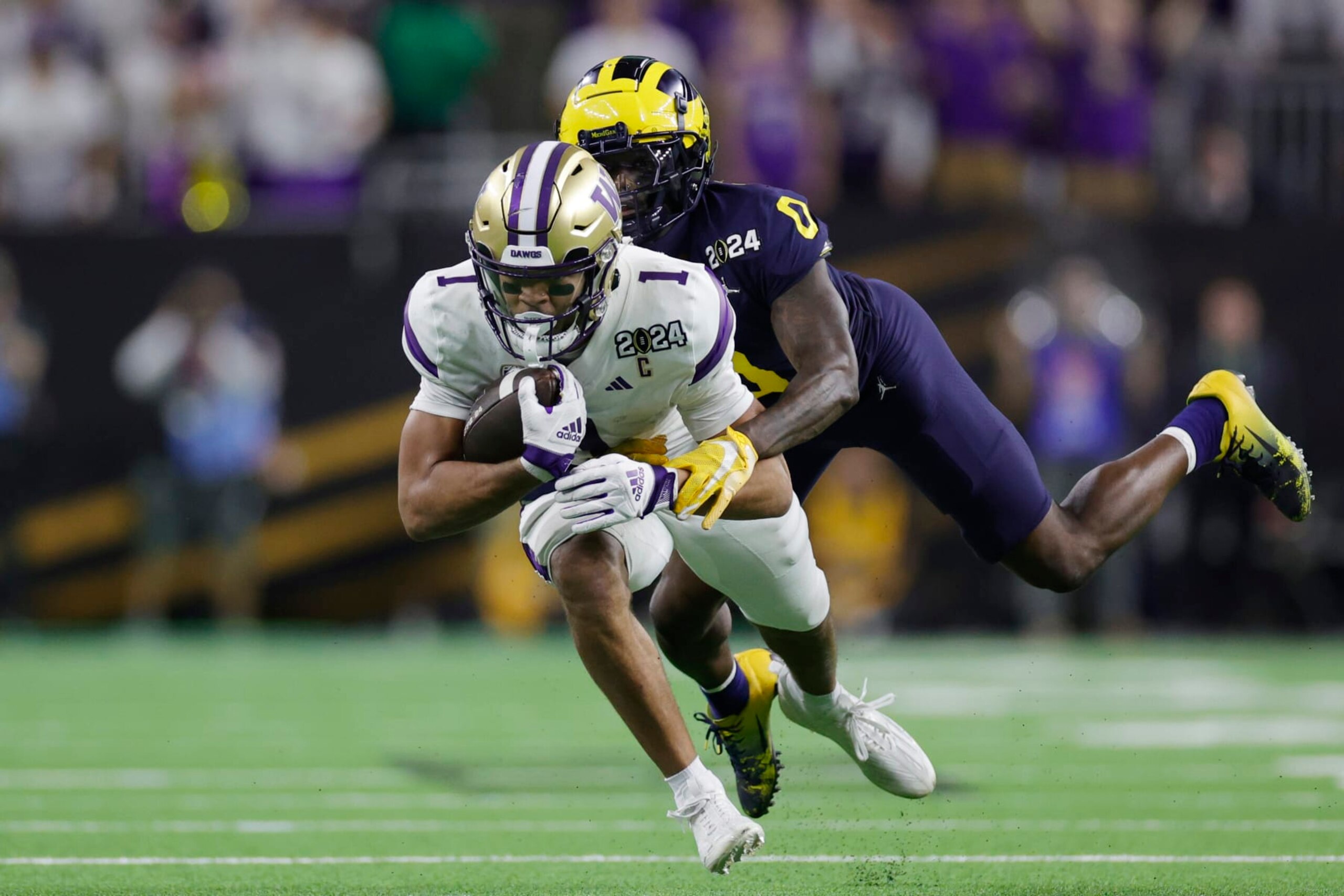 HOUSTON, TEXAS - JANUARY 08: Rome Odunze #1 of the Washington Huskies is tackled by Mike Sainristil #0 of the Michigan Wolverines in the second half during the 2024 CFP National Championship game at NRG Stadium on January 08, 2024 in Houston, Texas. (Photo by Carmen Mandato/Getty Images)