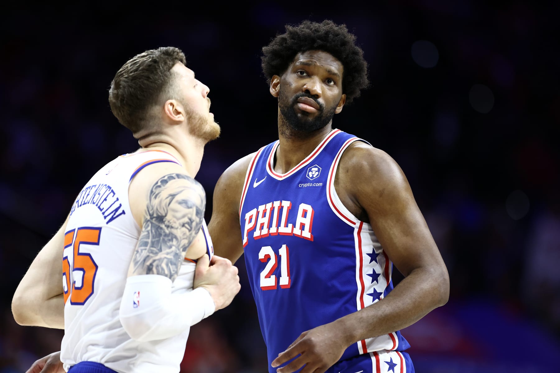 PHILADELPHIA, PENNSYLVANIA - APRIL 25: Joel Embiid #21 of the Philadelphia 76ers looks on past Isaiah Hartenstein #55 of the New York Knicks during the first quarter game three of the Eastern Conference First Round Playoffs at the Wells Fargo Center on April 25, 2024 in Philadelphia, Pennsylvania. NOTE TO USER: User expressly acknowledges and agrees that, by downloading and/or using this Photograph, user is consenting to the terms and conditions of the Getty Images License Agreement. (Photo by Tim Nwachukwu/Getty Images)