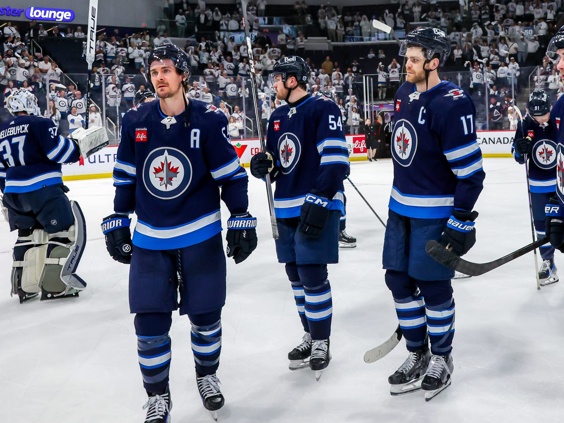 WINNIPEG, CANADA - APRIL 30: Mark Scheifele #55, Dylan Samberg #54, and Adam Lowry #17 of the Winnipeg Jets look on in disappointment following a 6-3 loss to the Colorado Avalanche in Game Five of the First Round of the 2024 Stanley Cup Playoffs at Canada Life Centre on April 30, 2024 in Winnipeg, Manitoba, Canada. (Photo by Jonathan Kozub/NHLI via Getty Images)