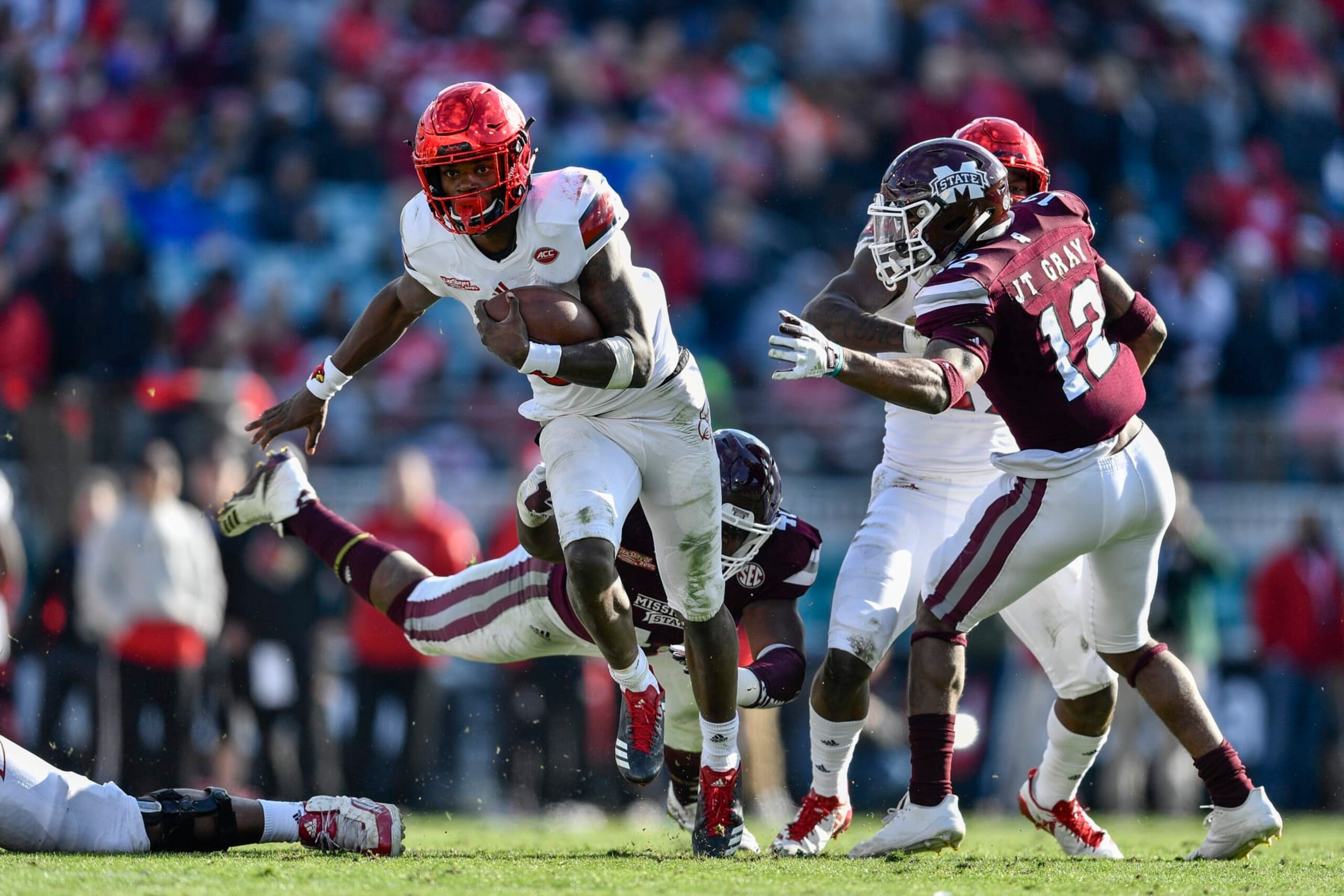 JACKSONVILLE, FL - DECEMBER 30: University of Louisville Cardinals quarterback Lamar Jackson (8) breaks a tackle during the second half of the TaxSlayer Bowl game between the Louisville Cardinals and the Mississippi State Bulldogs on December 30, 2017, at Everbank Field in Jacksonville, FL. Mississippi State defeated Louisville 31-27. (Photo by Roy K. Miller/Icon Sportswire via Getty Images)