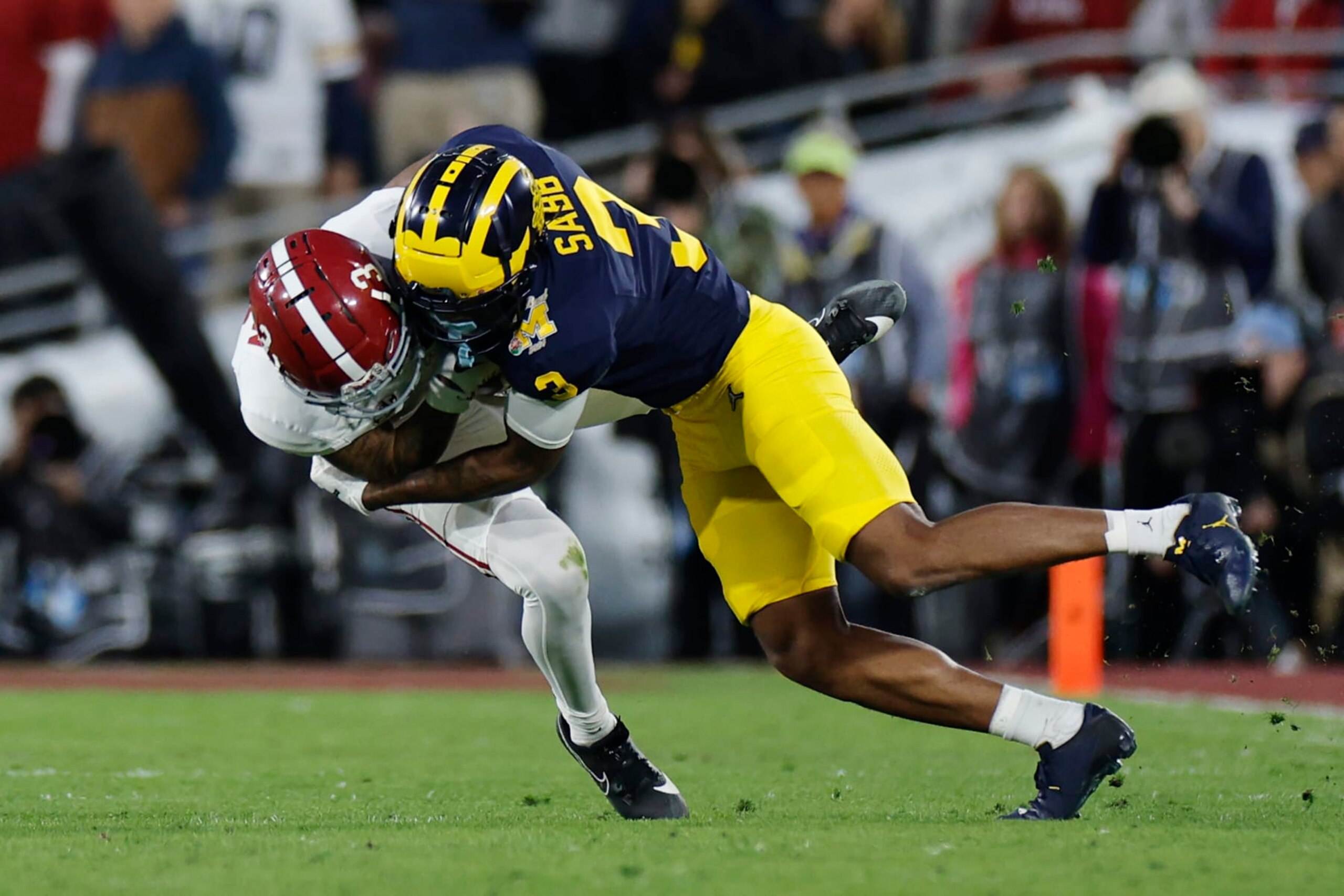 PASADENA, CALIFORNIA - JANUARY 01: Jermaine Burton #3 of the Alabama Crimson Tide runs with the ball while being tackled by Keon Sabb #3 of the Michigan Wolverines in the fourth quarter during the CFP Semifinal Rose Bowl Game at Rose Bowl Stadium on January 01, 2024 in Pasadena, California. (Photo by Kevork Djansezian/Getty Images)
