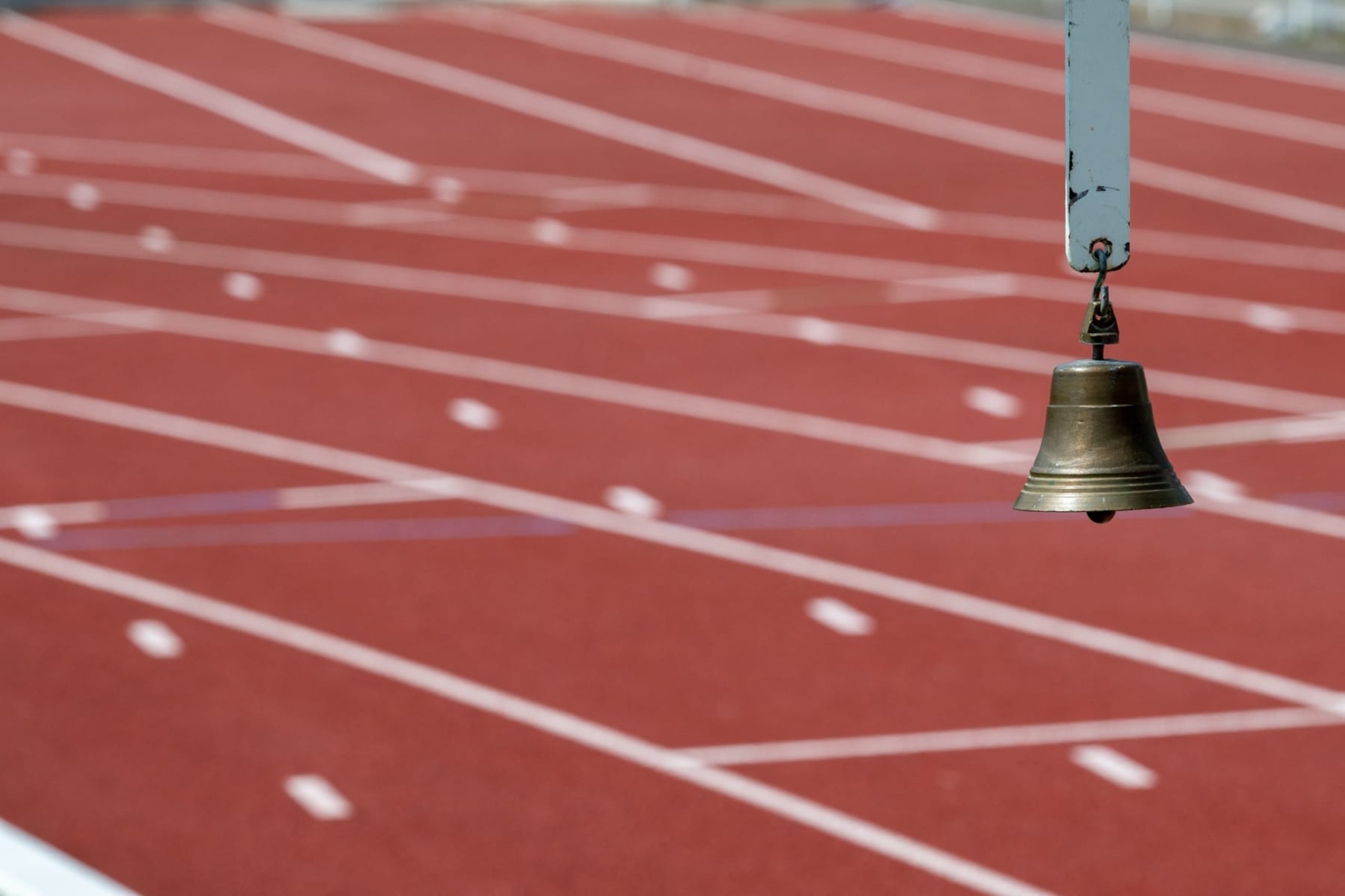 Close-up of the bell used to announce the last lap, the track blurred in the background, in Louis Boyer stadium, Gien, France on May 12, 2024. (Photo by Frederic Moreau / Hans Lucas / Hans Lucas via AFP) (Photo by FREDERIC MOREAU/Hans Lucas/AFP via Getty Images)