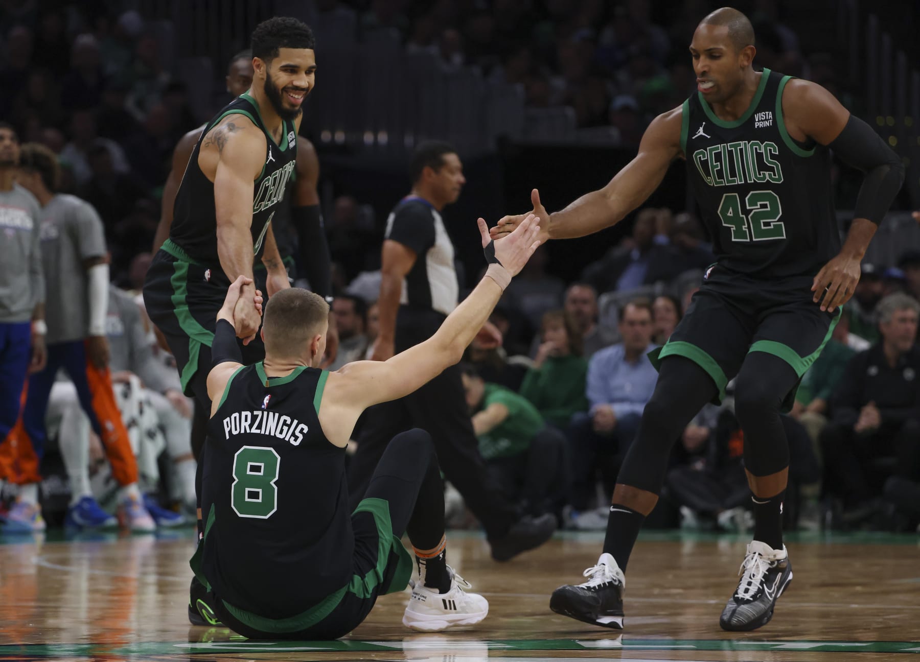 Boston, MA - November 13: Boston Celtics C Kristaps Porzingis is helped up off the court by teammates Jayson Tatum and Al Horford. The Celtics beat the New York Knicks, 114-98. (Photo by Matthew J. Lee/The Boston Globe via Getty Images)