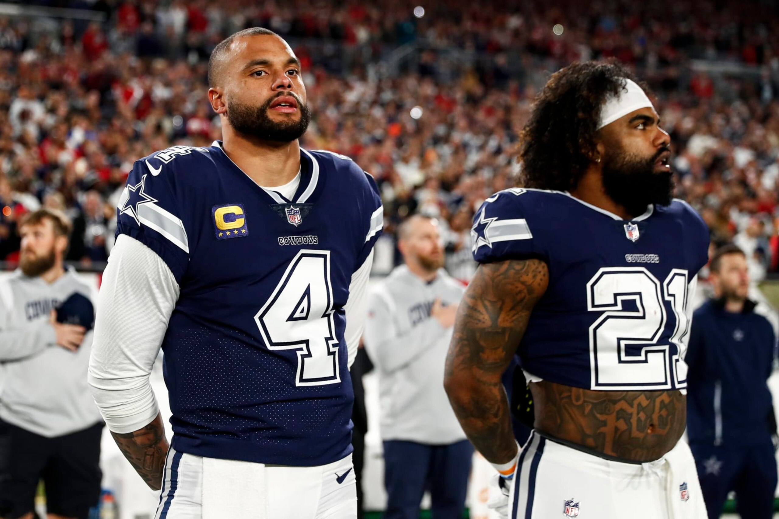 TAMPA, FL - JANUARY 16: Dak Prescott #4 and Ezekiel Elliott #21 of the Dallas Cowboys stand on the sidelines during the national anthem prior to an NFL wild card playoff football game against the Tampa Bay Buccaneers at Raymond James Stadium on January 16, 2023 in Tampa, Florida. (Photo by Kevin Sabitus/Getty Images)