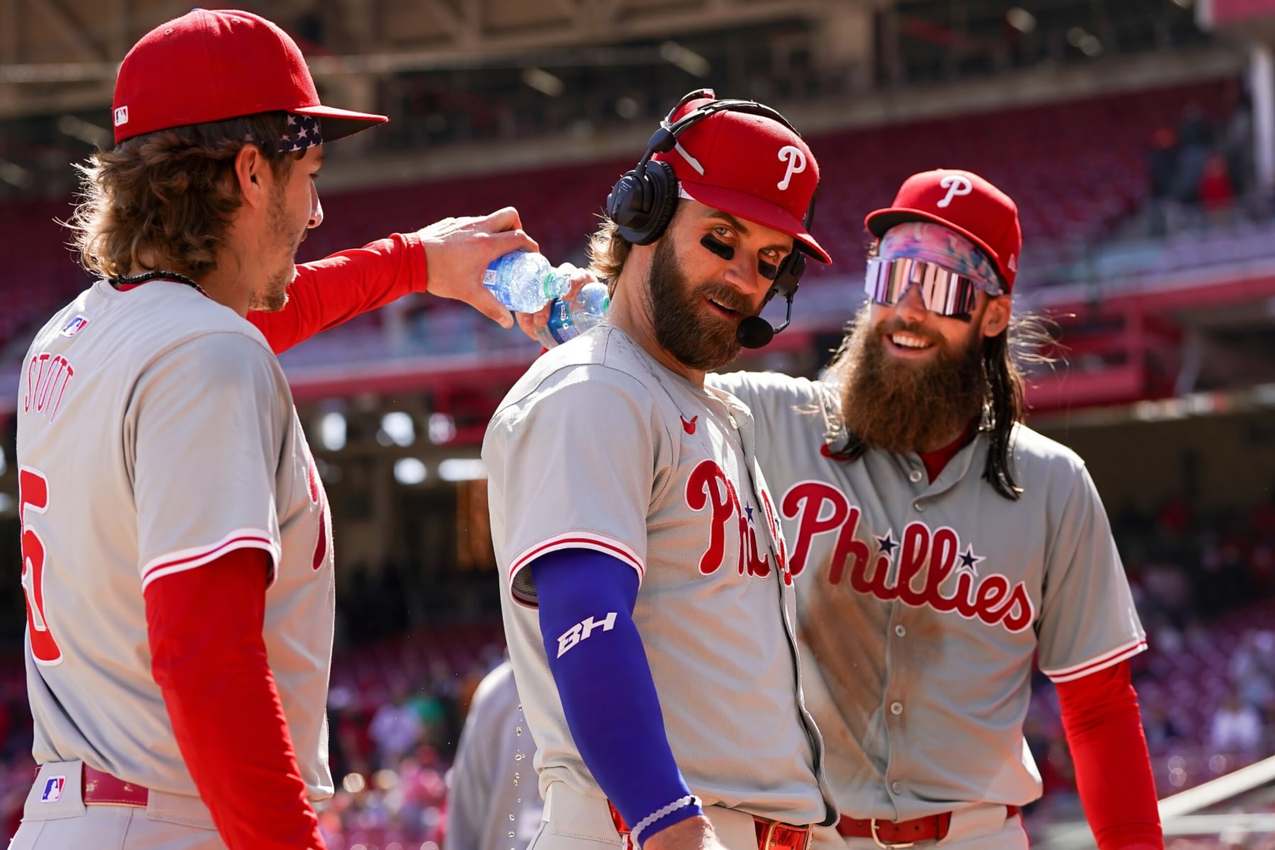 CINCINNATI, OHIO - APRIL 25: Bryson Stott #5 and Brandon Marsh #16 of the Philadelphia Phillies pour water on Bryce Harper #3 after beating the Cincinnati Reds 5-0 at Great American Ball Park on April 25, 2024 in Cincinnati, Ohio. (Photo by Dylan Buell/Getty Images)
