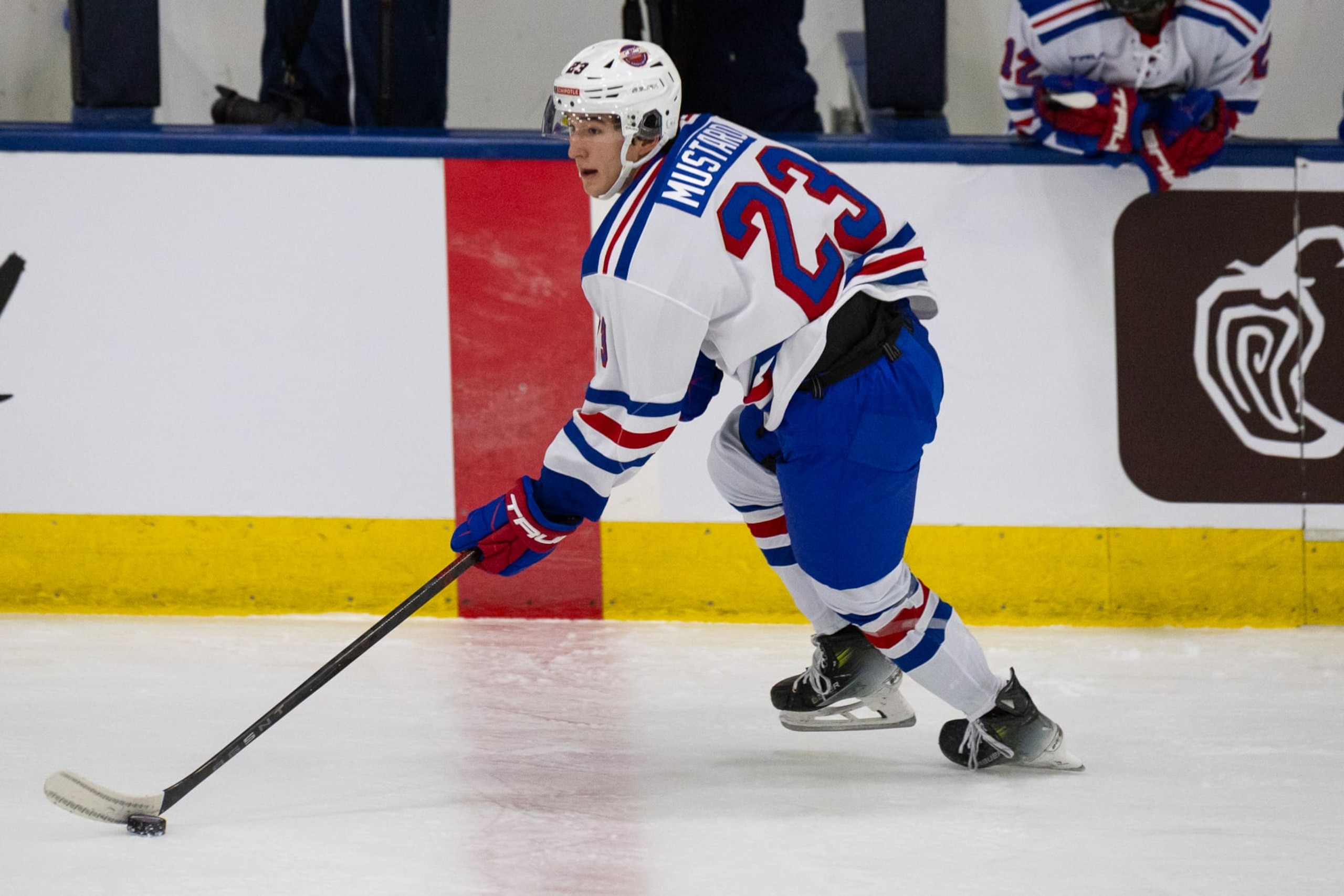PLYMOUTH, MICHIGAN - JANUARY 15: John Mustard #23 of Team White skates with the puck during Chipotle All-American Game between Team Blue and Team White at USA Hockey Arena on January 15, 2024 in Plymouth, Michigan. (Photo by Michael Miller/ISI Photos/Getty Images)