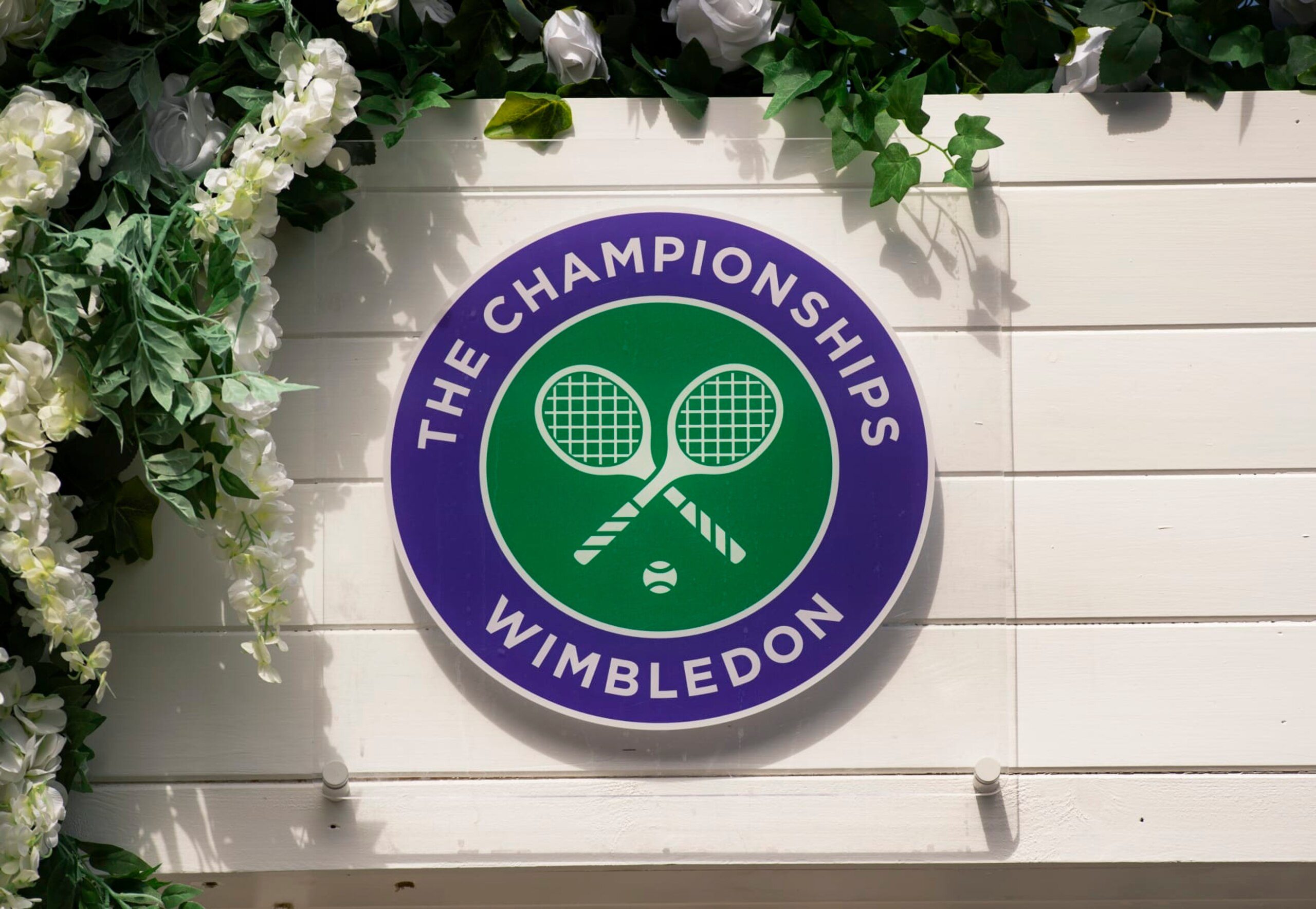 LONDON, ENGLAND - JULY 11: The Wimbledon logo surrounded by flowers during Day Ten of The Championships - Wimbledon 2019 at All England Lawn Tennis and Croquet Club on July 11, 2019 in London, England. (Photo by Visionhaus/Getty Images)
