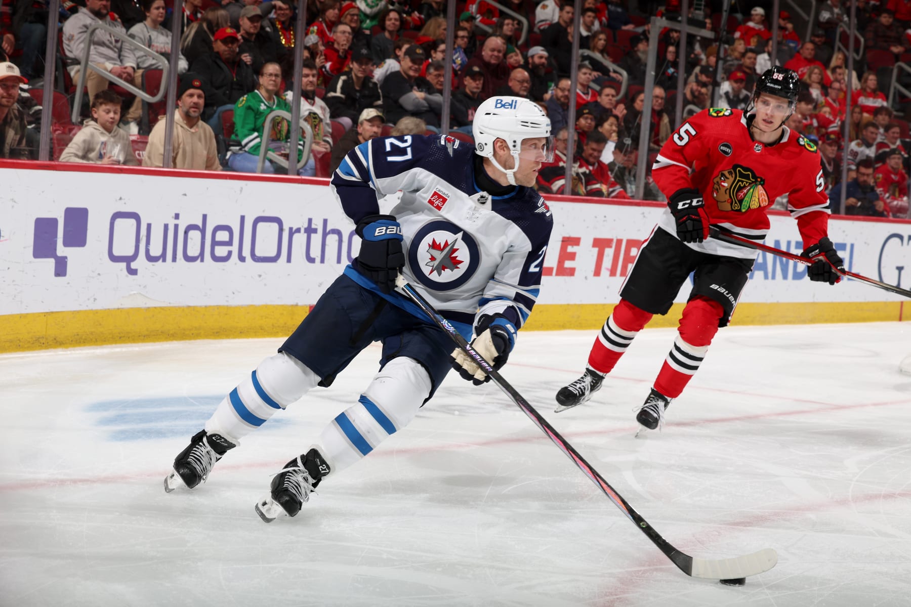CHICAGO, ILLINOIS - FEBRUARY 23: Nikolaj Ehlers #27 of the Winnipeg Jets controls the puck ahead of Kevin Korchinski #55 of the Chicago Blackhawks in the third period at the United Center on February 23, 2024 in Chicago, Illinois. (Photo by Chase Agnello-Dean/NHLI via Getty Images)