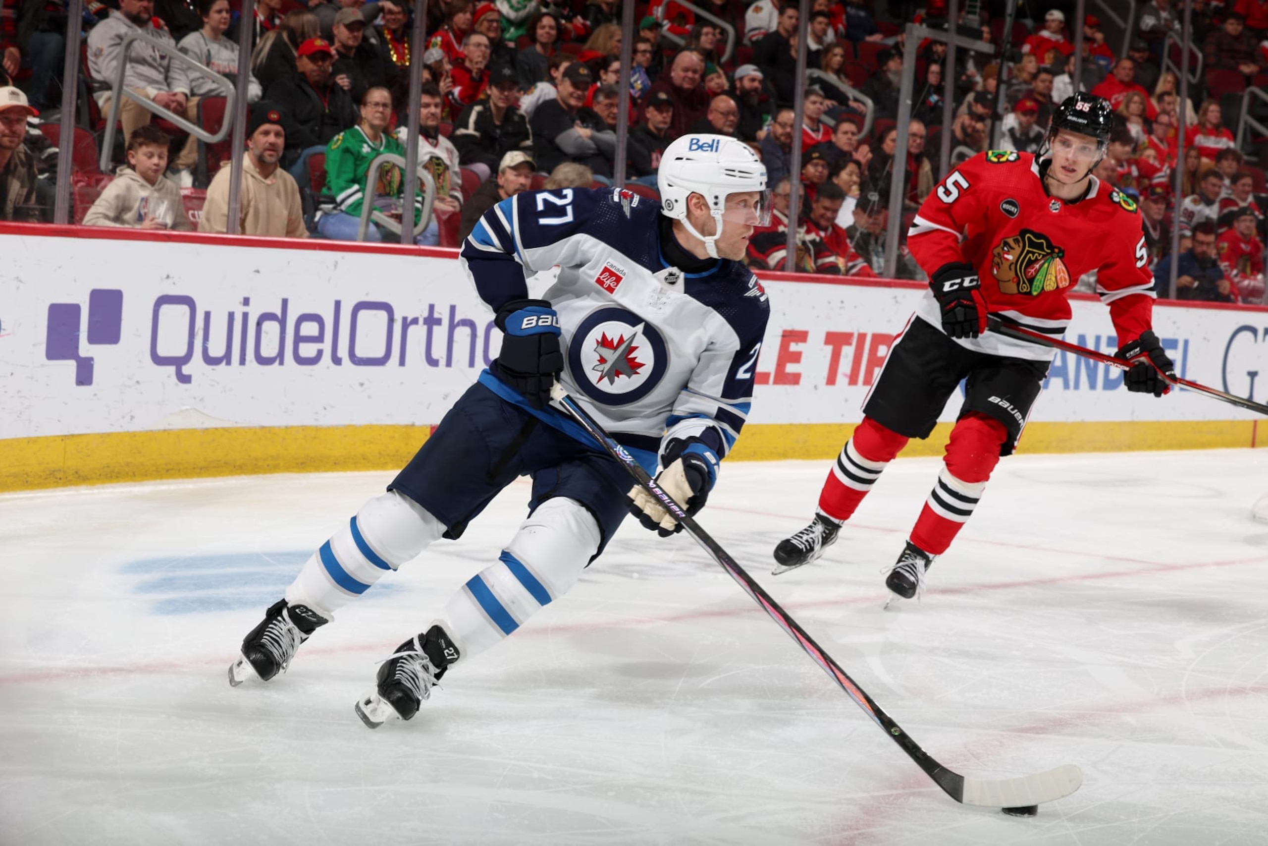 CHICAGO, ILLINOIS - FEBRUARY 23: Nikolaj Ehlers #27 of the Winnipeg Jets controls the puck ahead of Kevin Korchinski #55 of the Chicago Blackhawks in the third period at the United Center on February 23, 2024 in Chicago, Illinois. (Photo by Chase Agnello-Dean/NHLI via Getty Images)