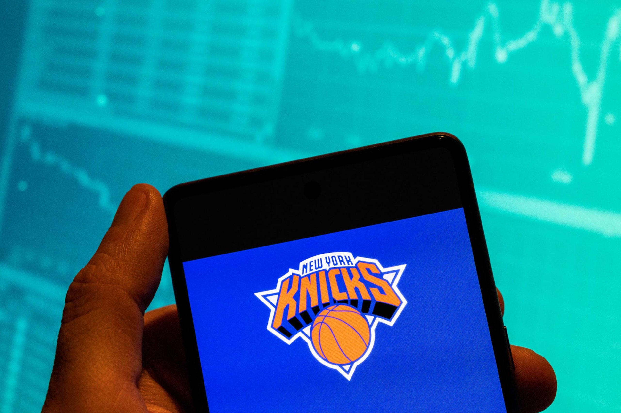 CHINA - 2023/02/15: In this photo illustration, the American professional basketball NBA team The New York Knicks logo is seen displayed on a smartphone with an economic stock exchange index graph in the background. (Photo Illustration by Budrul Chukrut/SOPA Images/LightRocket via Getty Images) CHINA - 2023/02/15: In this photo illustration, the American professional basketball NBA team The New York Knicks logo is seen displayed on a smartphone with an economic stock exchange index graph in the background. (Photo Illustration by Budrul Chukrut/SOPA Images/LightRocket via Getty Images)