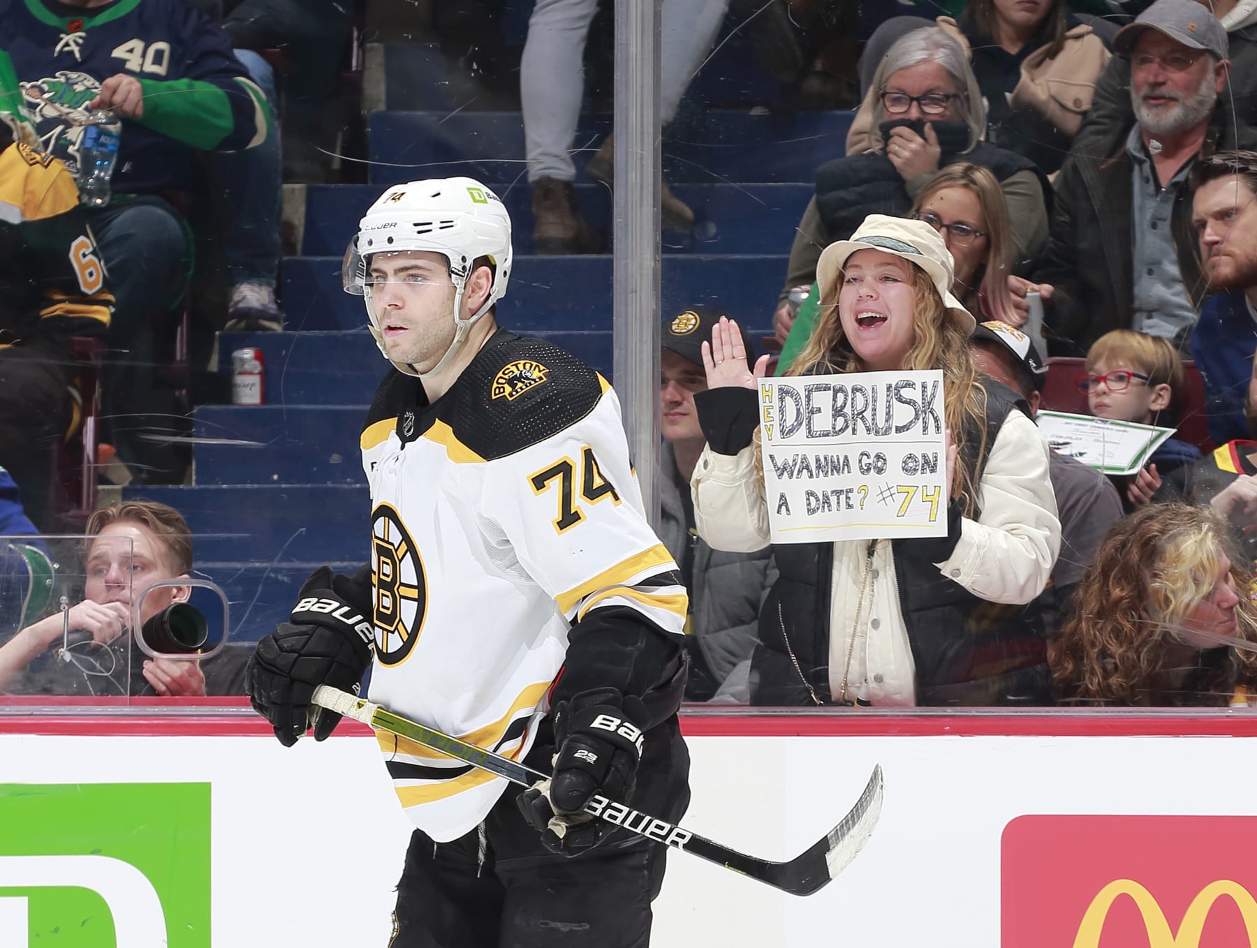 VANCOUVER, CANADA - FEBRUARY 25:  Jake DeBrusk #74 of the Boston Bruins skates by fan holding up a date request during the second period of their NHL game against the Vancouver Canucks at Rogers Arena February 25, 2023 in Vancouver, British Columbia, Canada.  (Photo by Jeff Vinnick/NHLI via Getty Images)