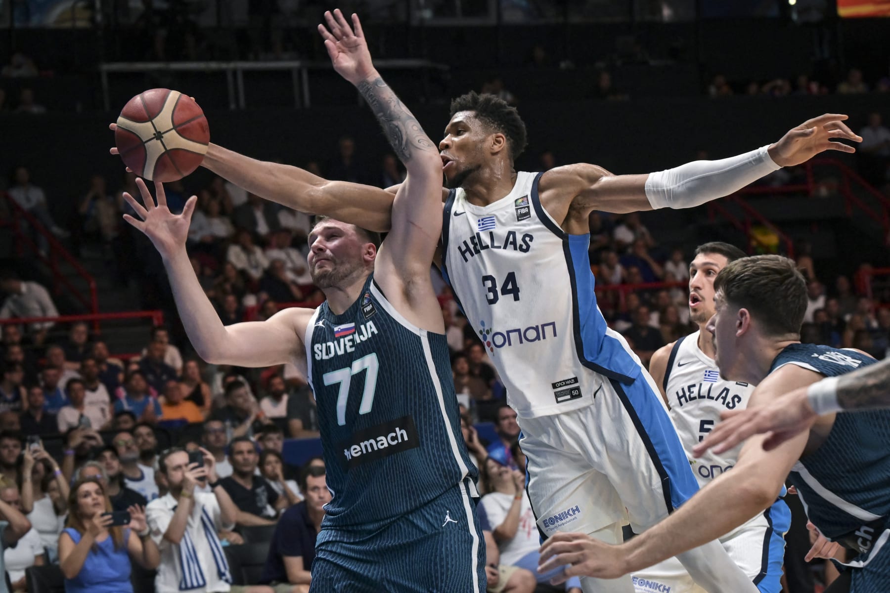 Greece's Giannis Antentokoumbo (C) jumps for a rebound with Slovenia's Luka Doncic (L) during the 2024 FIBA Olympic Qualifying Tournament semi-final basketball match between Dominican Republic and Greece at the Peace and Friendship Stadium in Athens, on July 6, 2024. (Photo by Aris MESSINIS / AFP) (Photo by ARIS MESSINIS/AFP via Getty Images)