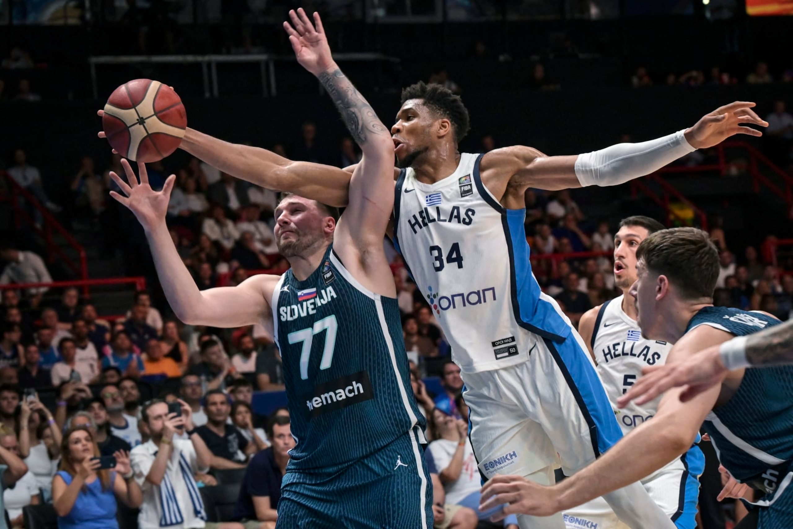 Greece's Giannis Antentokoumbo (C) jumps for a rebound with Slovenia's Luka Doncic (L) during the 2024 FIBA Olympic Qualifying Tournament semi-final basketball match between Dominican Republic and Greece at the Peace and Friendship Stadium in Athens, on July 6, 2024. (Photo by Aris MESSINIS / AFP) (Photo by ARIS MESSINIS/AFP via Getty Images) Greece's Giannis Antentokoumbo (C) jumps for a rebound with Slovenia's Luka Doncic (L) during the 2024 FIBA Olympic Qualifying Tournament semi-final basketball match between Dominican Republic and Greece at the Peace and Friendship Stadium in Athens, on July 6, 2024. (Photo by Aris MESSINIS / AFP) (Photo by ARIS MESSINIS/AFP via Getty Images)