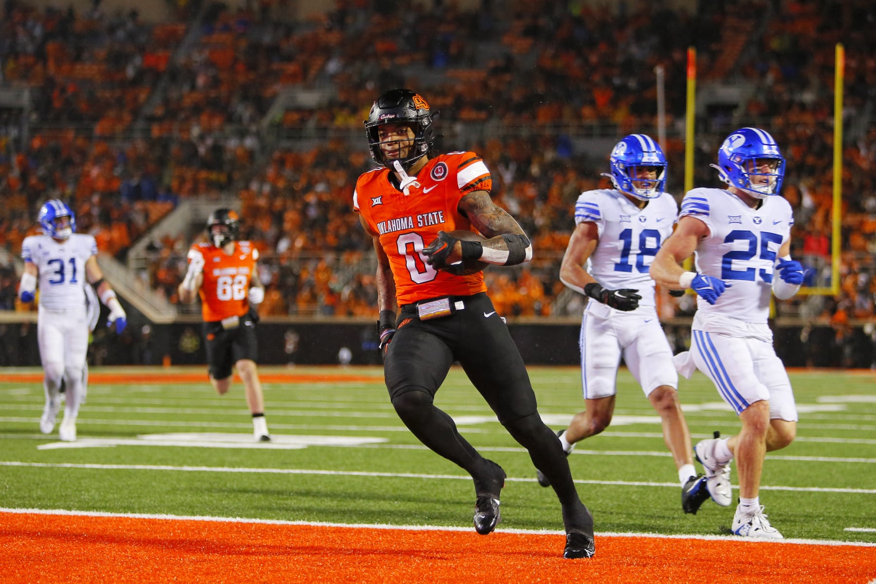 STILLWATER, OK - NOVEMBER 25:  Running back Ollie Gordon II #0 of the Oklahoma State Cowboys scores a touchdown on a 15-yard run past safety Talan Alfrey #25 and linebacker Ace Kaufusi #18 of the BYU Cougars in the fourth quarter at Boone Pickens Stadium on November 25, 2023 in Stillwater, Oklahoma.  Gordon ran for 166 yards and five touchdowns as the Oklahoma State won 40-34 in double overtime.  (Photo by Brian Bahr/Getty Images)