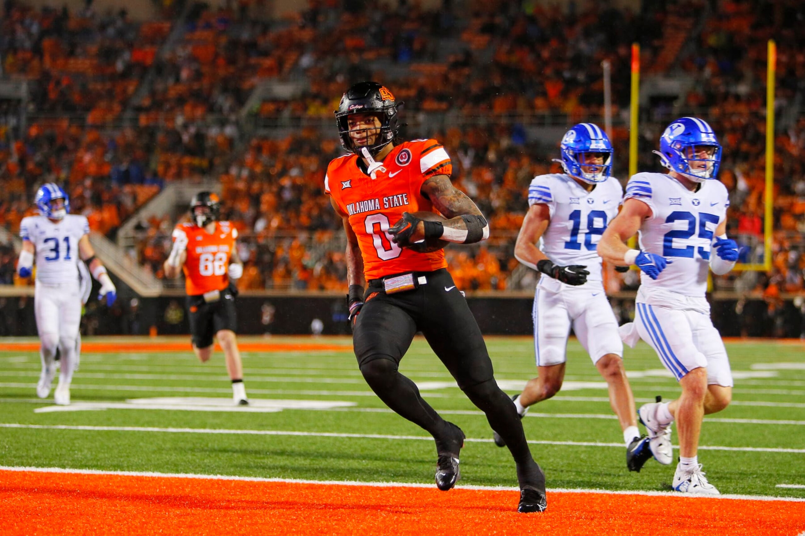 STILLWATER, OK - NOVEMBER 25:  Running back Ollie Gordon II #0 of the Oklahoma State Cowboys scores a touchdown on a 15-yard run past safety Talan Alfrey #25 and linebacker Ace Kaufusi #18 of the BYU Cougars in the fourth quarter at Boone Pickens Stadium on November 25, 2023 in Stillwater, Oklahoma.  Gordon ran for 166 yards and five touchdowns as the Oklahoma State won 40-34 in double overtime.  (Photo by Brian Bahr/Getty Images)