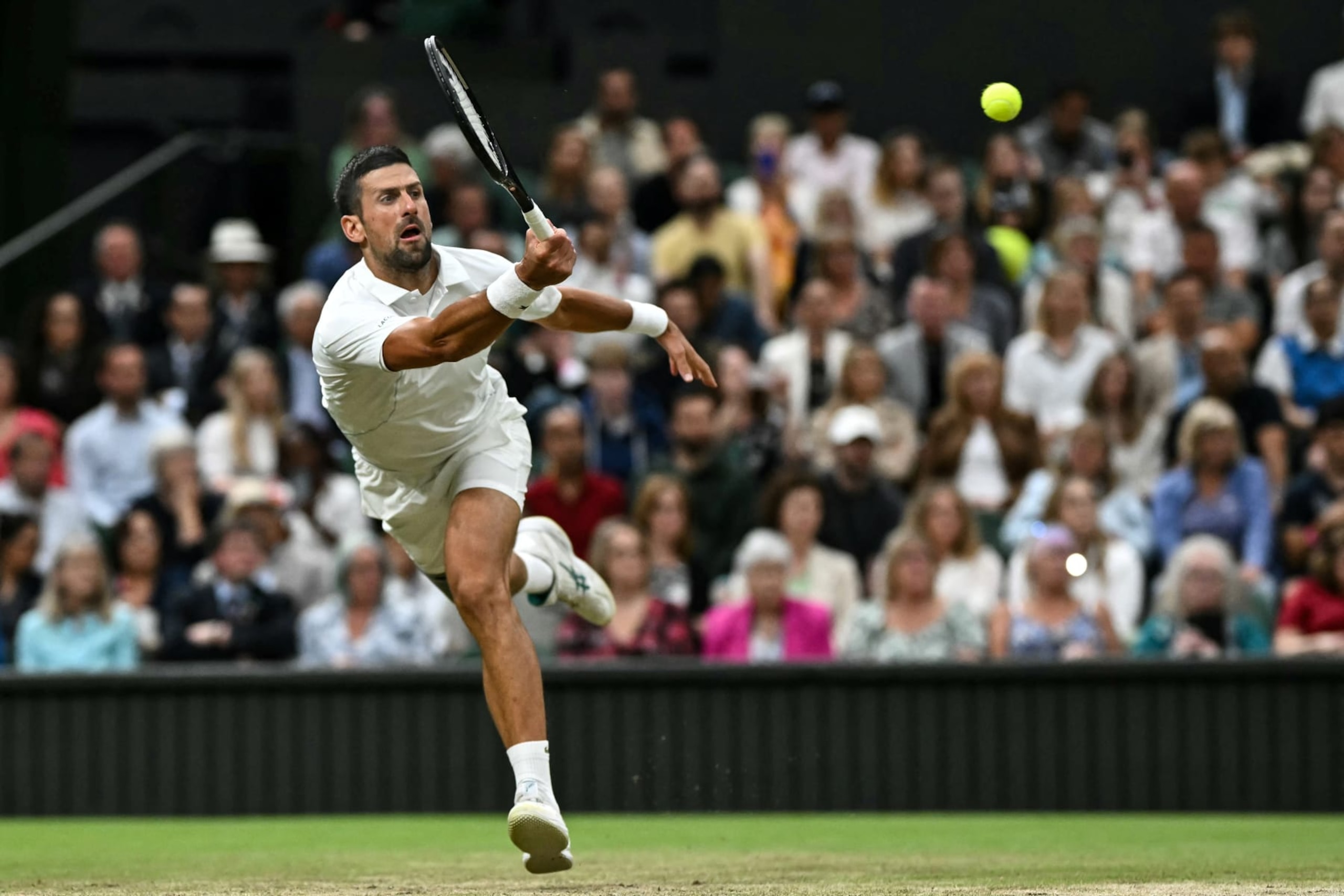 Serbia's Novak Djokovic returns the ball to Denmark's Holger Rune during their men's singles tennis match on the eighth day of the 2024 Wimbledon Championships at The All England Lawn Tennis and Croquet Club in Wimbledon, southwest London, on July 8, 2024. (Photo by Ben Stansall / AFP) / RESTRICTED TO EDITORIAL USE (Photo by BEN STANSALL/AFP via Getty Images)