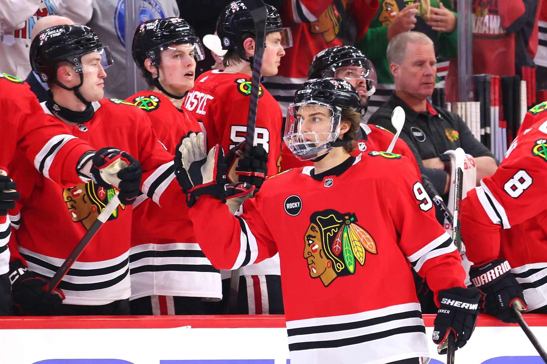 CHICAGO, ILLINOIS - APRIL 12: Connor Bedard #98 of the Chicago Blackhawks high fives teammates after assisting a goal scored by Philipp Kurashev #23 during the second period against the Nashville Predators at the United Center on April 12, 2024 in Chicago, Illinois. (Photo by Michael Reaves/Getty Images)