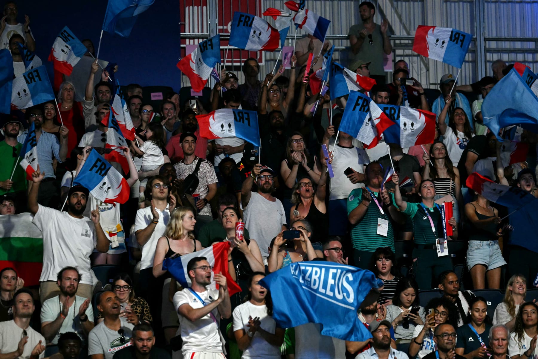 Supporters of France's Davina Michel cheer after her win against Thailand's Baison Manikon in the women's 75kg preliminaries round of 16 boxing match during the Paris 2024 Olympic Games at the North Paris Arena, in Villepinte on July 31, 2024. (Photo by MOHD RASFAN / AFP) (Photo by MOHD RASFAN/AFP via Getty Images)